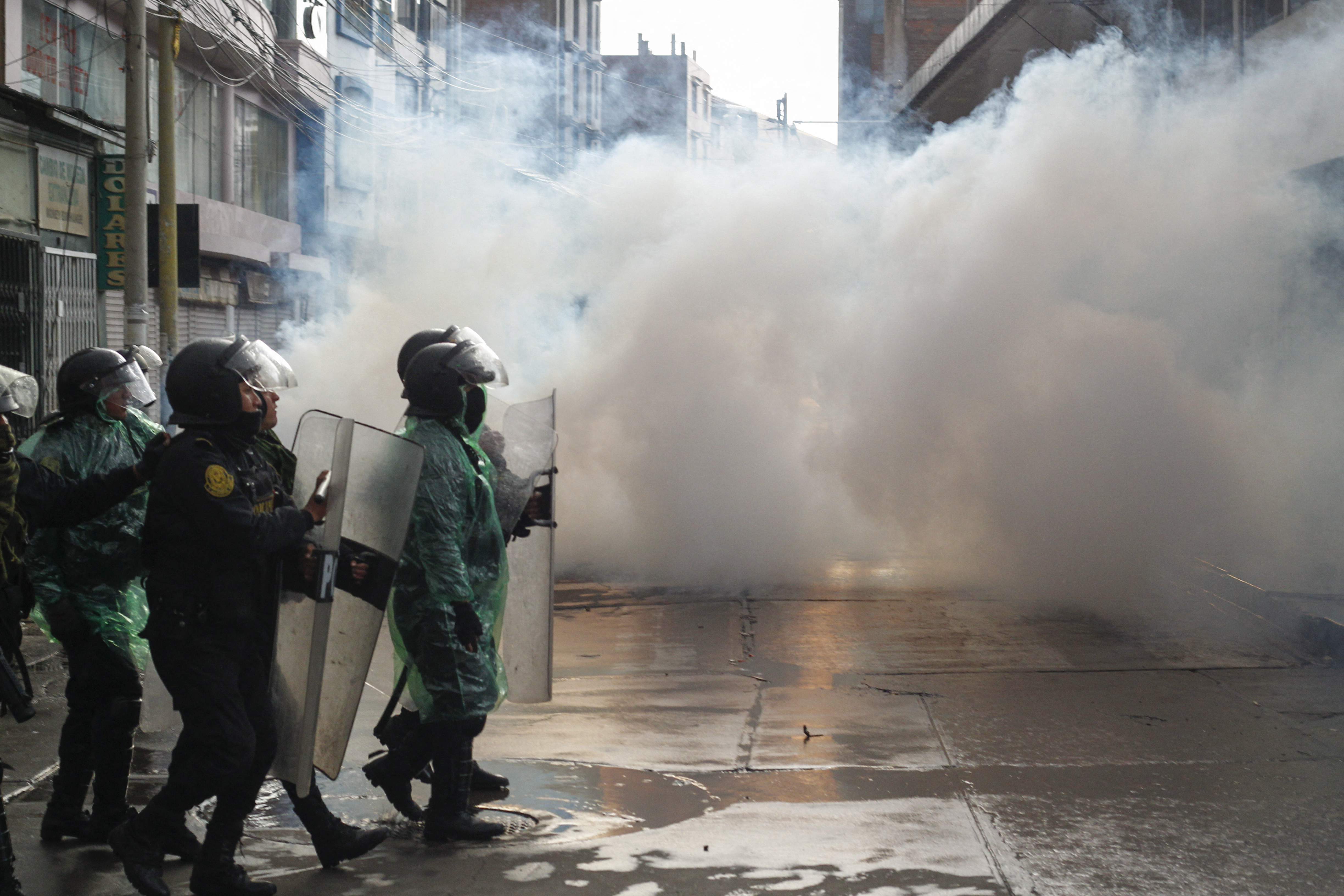 Riot police with transparent shields in clouds of tear gas during anti-government protests