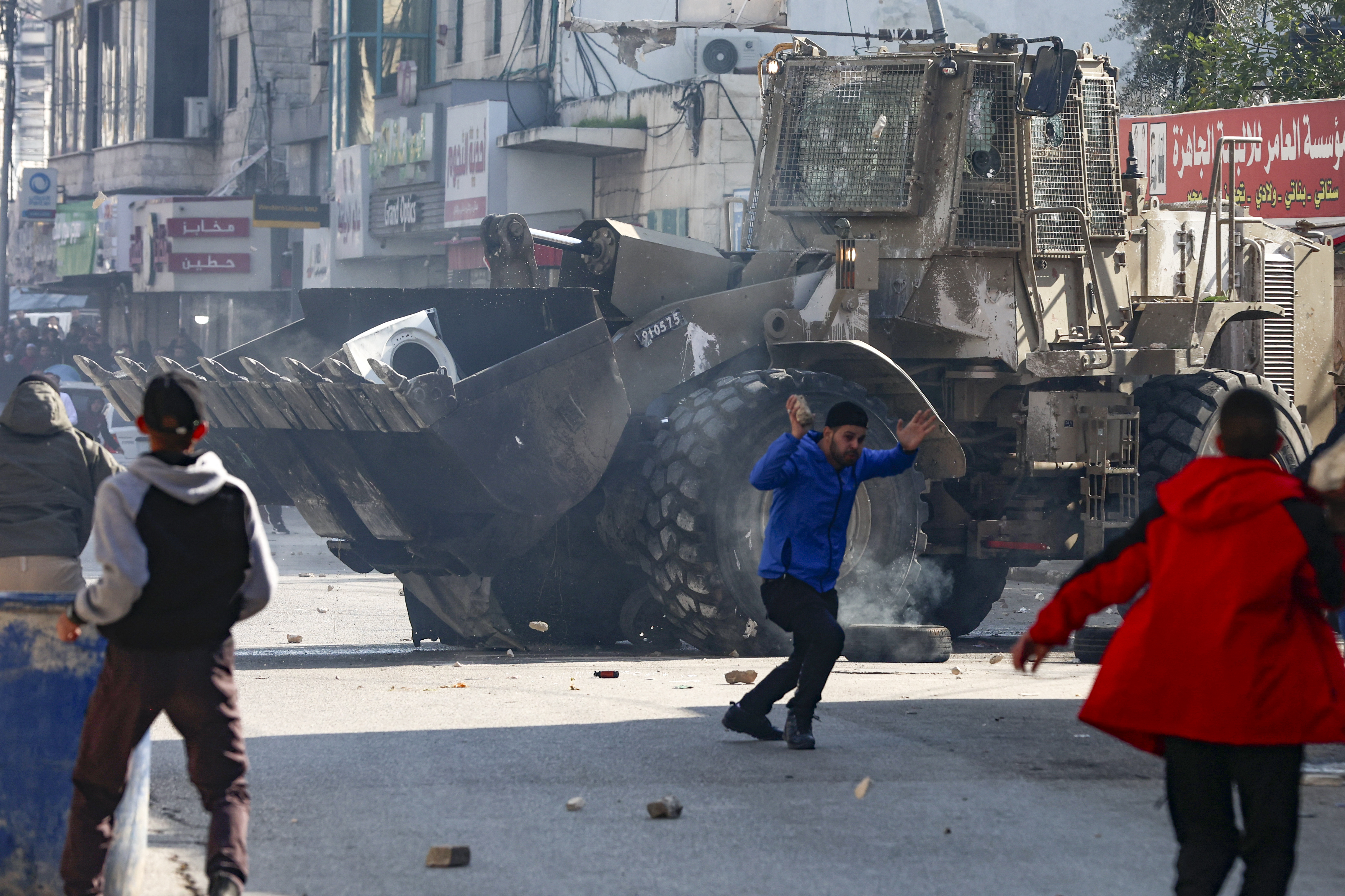 Palestinians hurl rocks at an Israeli army bulldozer, during confrontations in the occupied-West Bank