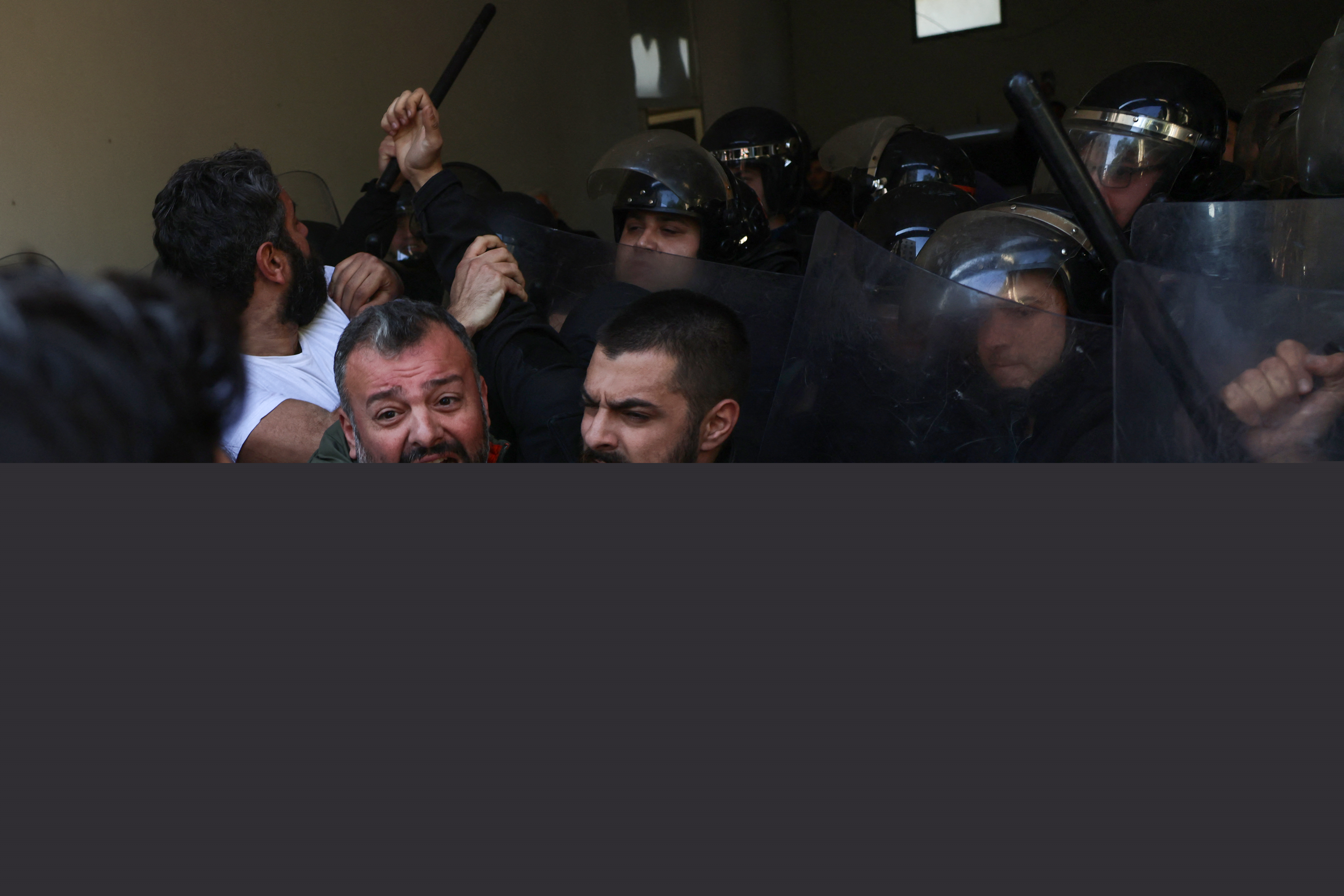 Security forces push back relatives of victims of the 2020 Beirut port explosion, trying to push their way into the palace of justice after breaking the lock of the entrance gate, during a rally outside the building in the Lebanese capital Beirut, to support the judge investigating the disaster, on January 26, 2023, after he was charged by the country's top prosecutor in the highly political case. - One of history's biggest non-nuclear explosions, the August 4, 2020 blast destroyed much of the Lebanese capital's port and surrounding areas, killing more than 215 people and injuring over 6,500. No official has been held accountable for the disaster. (Photo by Joseph EID / AFP)