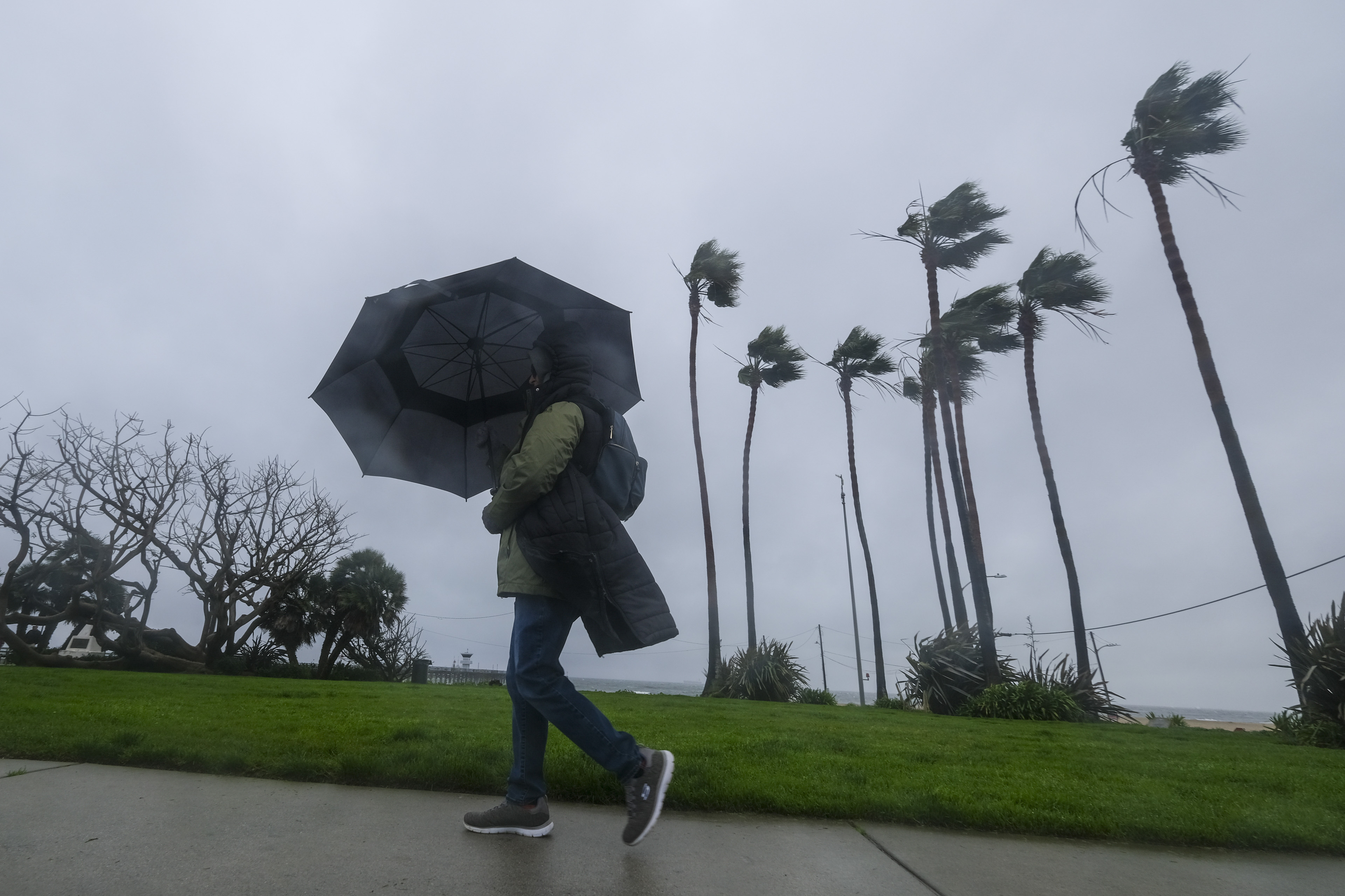 A woman walks with wind-beaten umbrella in California