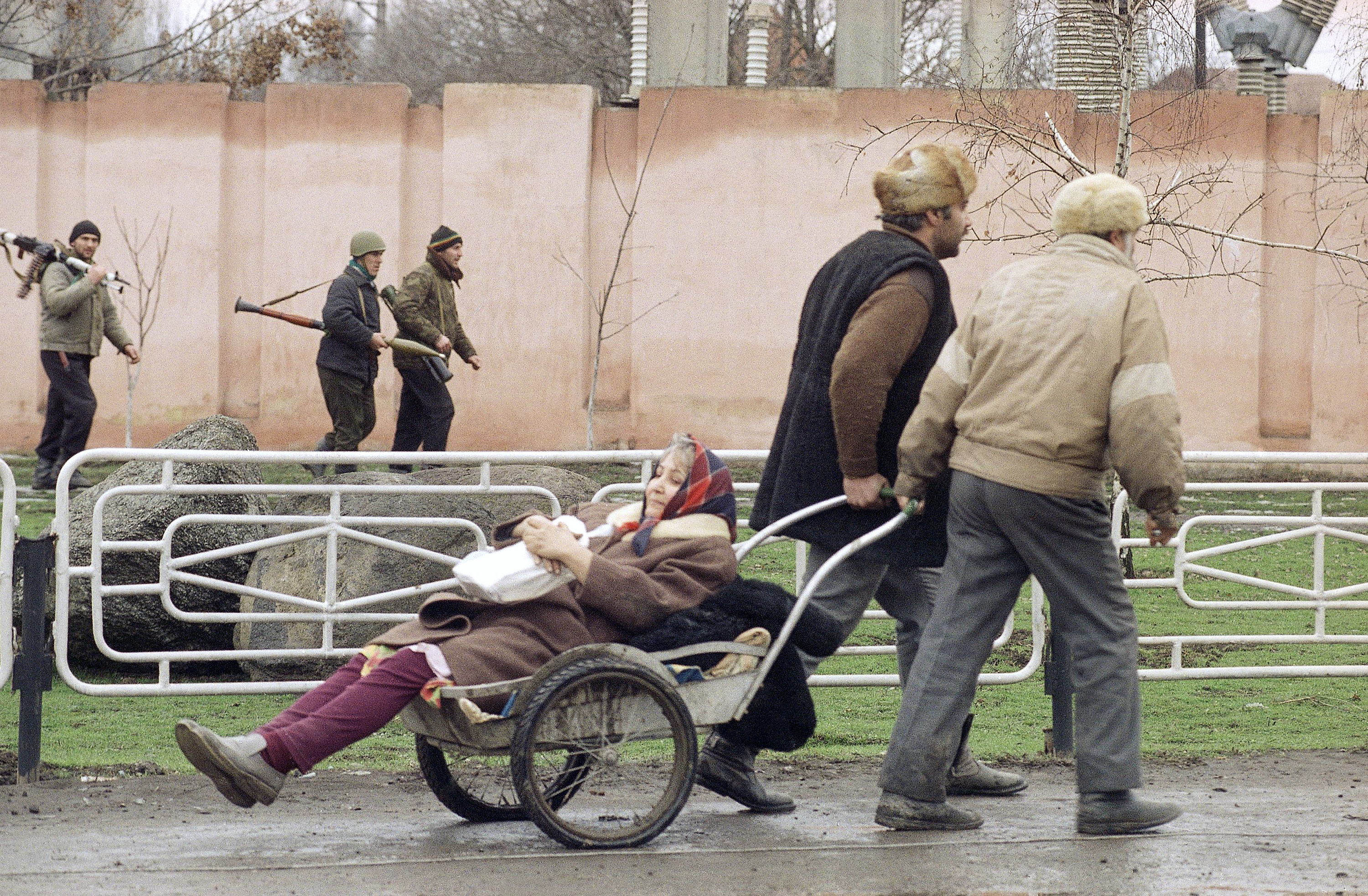 Chechens wheel an elderly woman in a cart away from the fighting in central Grozny on January 8, 1995