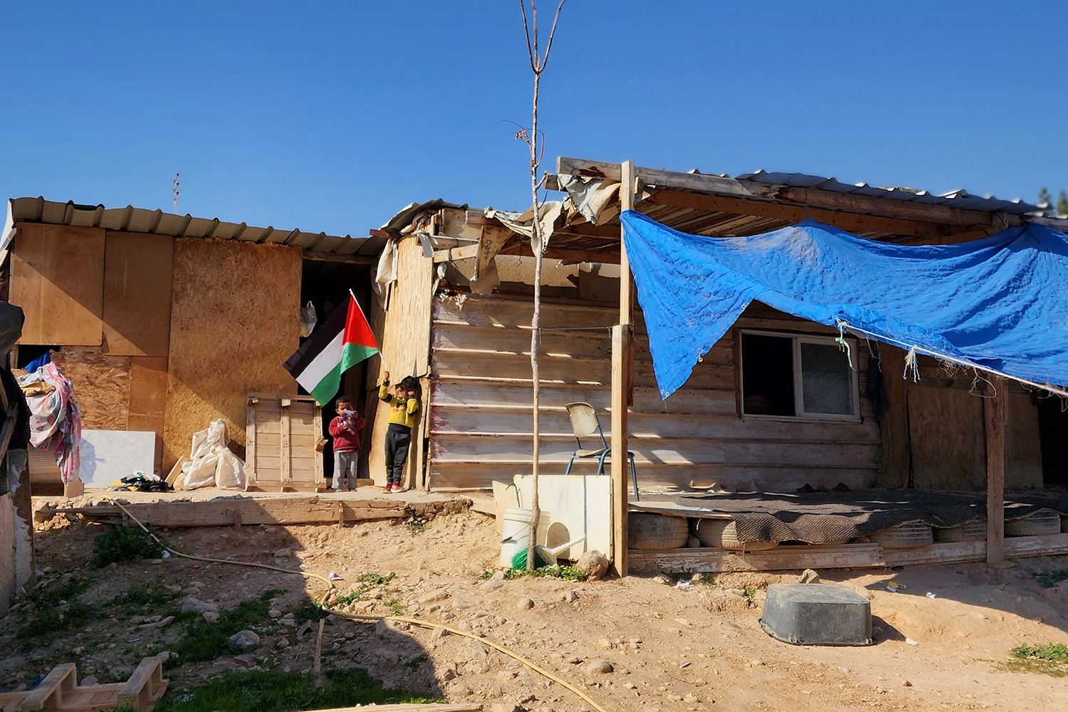 Children raise a Palestinian flag in Khan al-Ahmar, West Bank