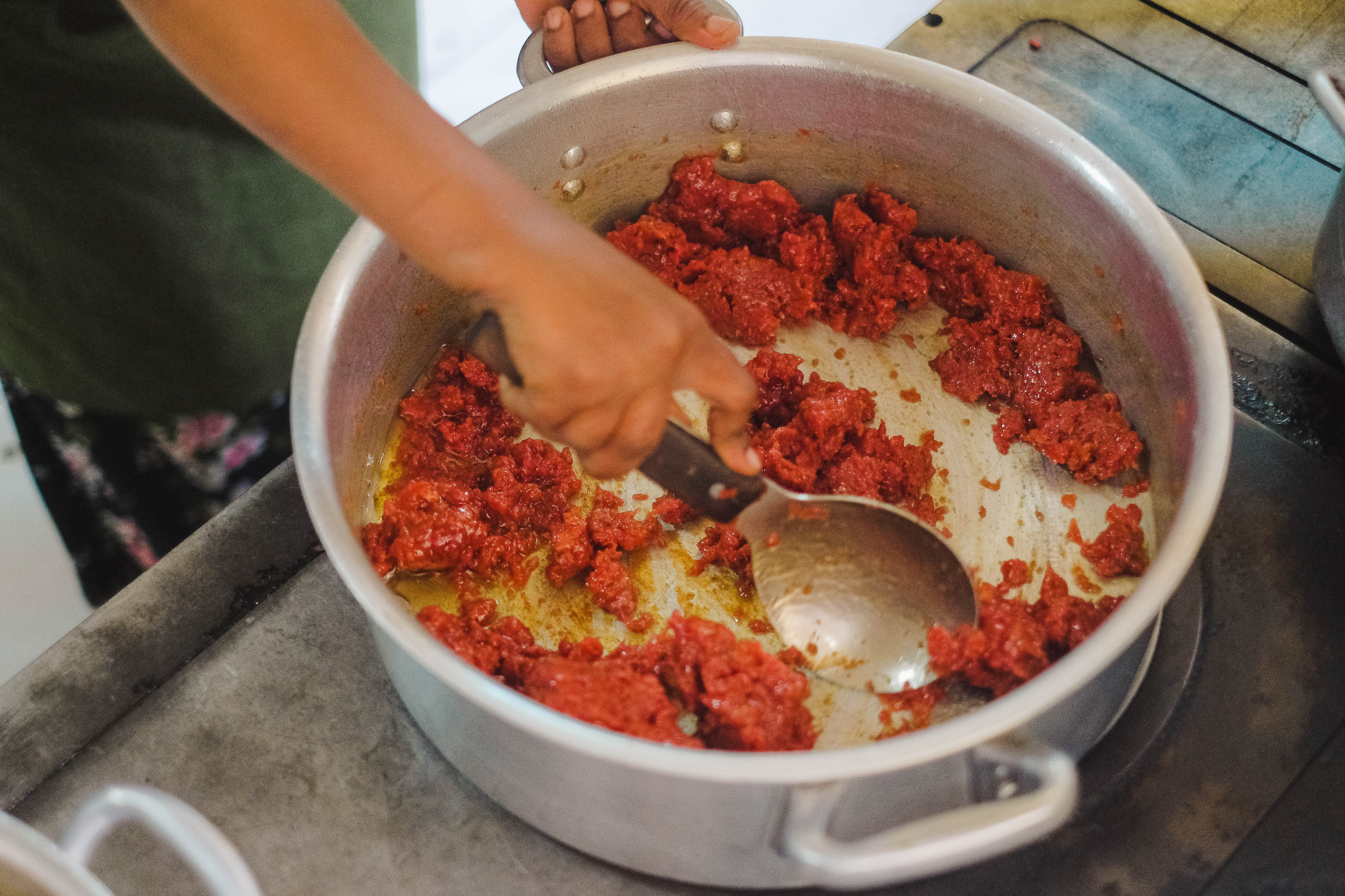 A chef moves ground kitfo quickly around a pot to prepare for a customer