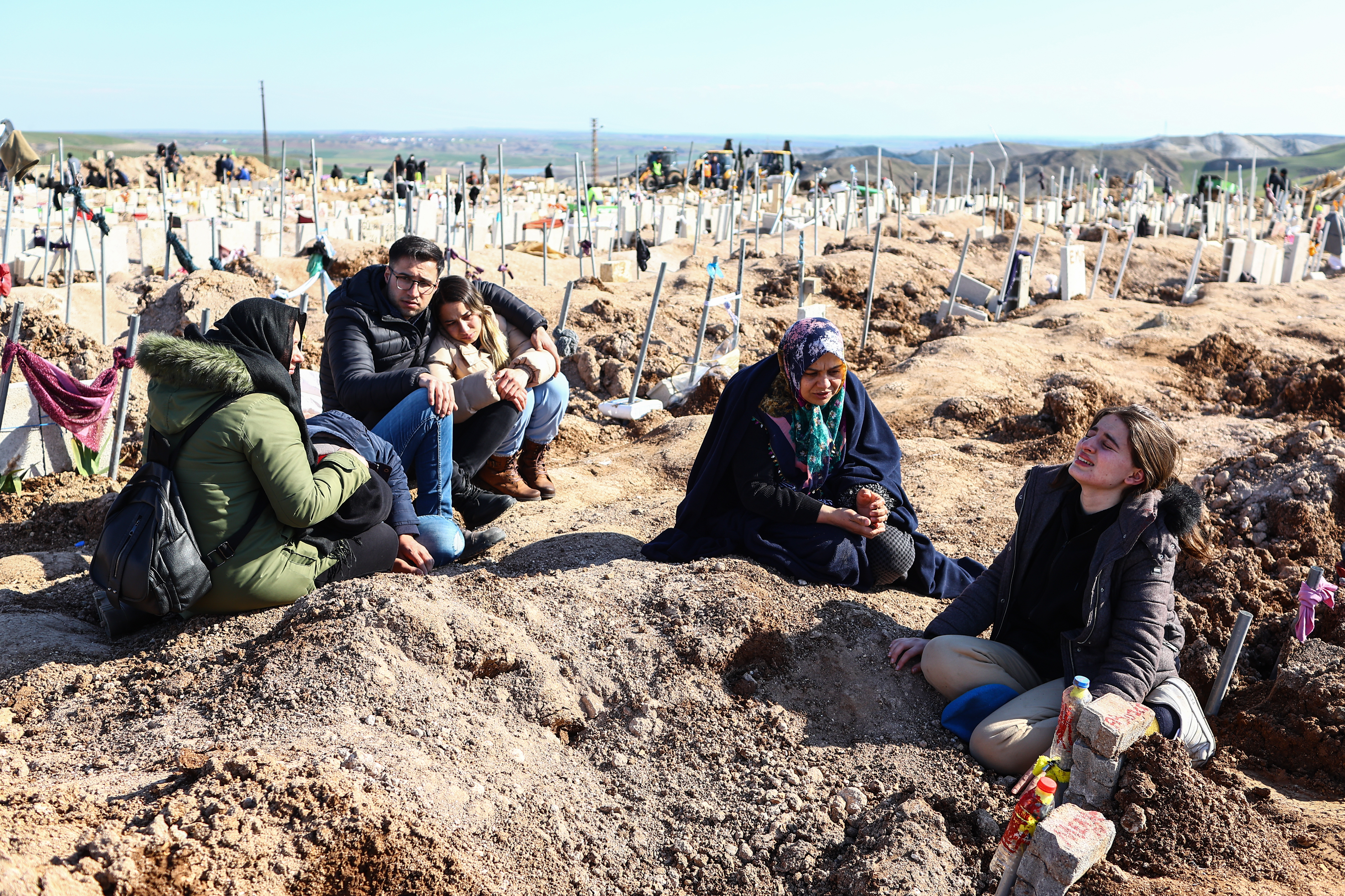 People mourn their relatives at a mass grave area following a major earthquake in Adiyaman, southeastern Turkey, 11 February 2023. More than 24,000 people have died and thousands more are injured after two major earthquakes struck southern Turkey and northern Syria on 06 February. Authorities fear the death toll will keep climbing as rescuers look for survivors across the region.