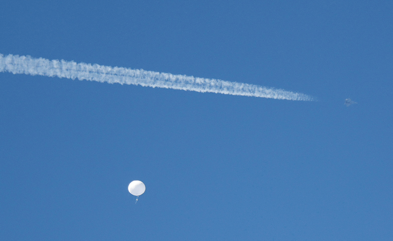 FILE PHOTO: A jet flies by a suspected Chinese spy balloon as it floats off the coast in Surfside Beach, South Carolina, U.S. February 4, 2023. REUTERS/Randall Hill/File Photo