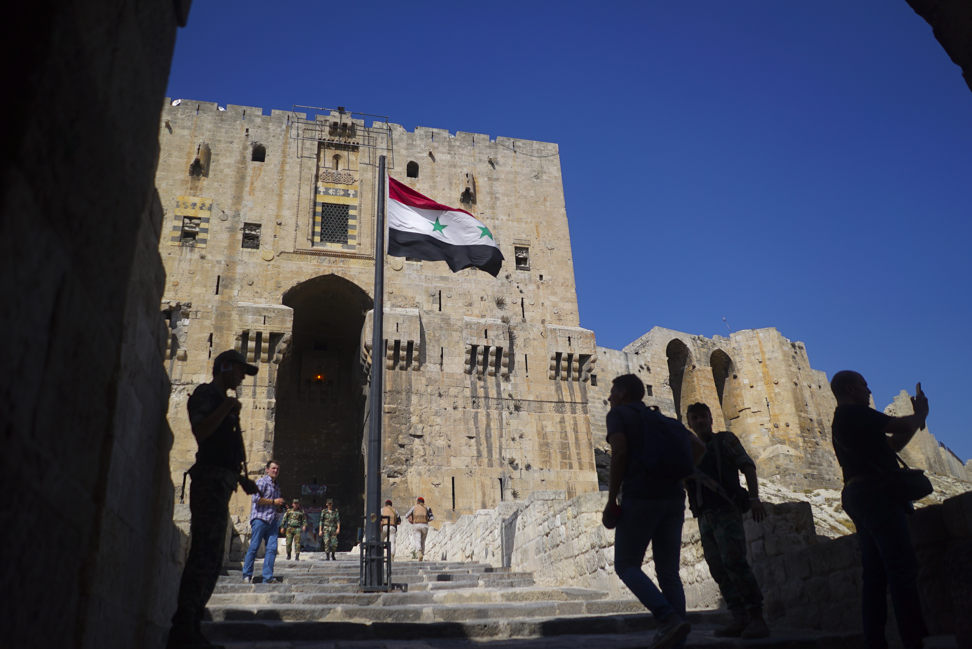 People walk into the Citadel, Aleppo's famed fortress where much of the fierce fighting took place in 2016, in Syria, Tuesday, Sept. 12, 2017. The recapture of eastern Aleppo in December 2016, one of the deadliest episodes of the Syrian civil war, was a landmark victory for Assad's forces in the conflict, now in its seventh year, but it left the area in ruins. (AP Photo/Nataliya Vasilyeva)