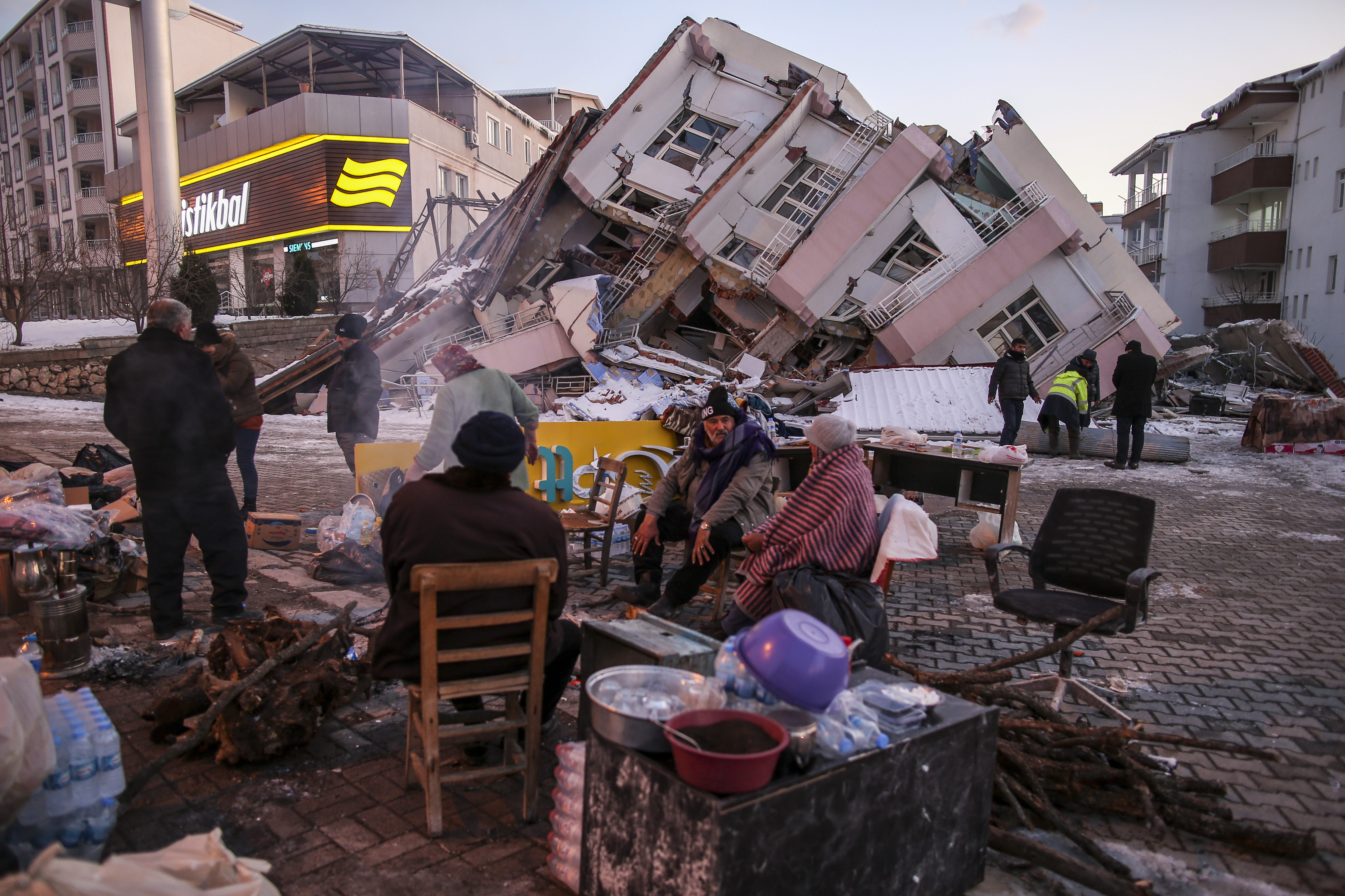 People stand by collapsed buildings in Golbasi, in Adiyaman province, southern Turkey