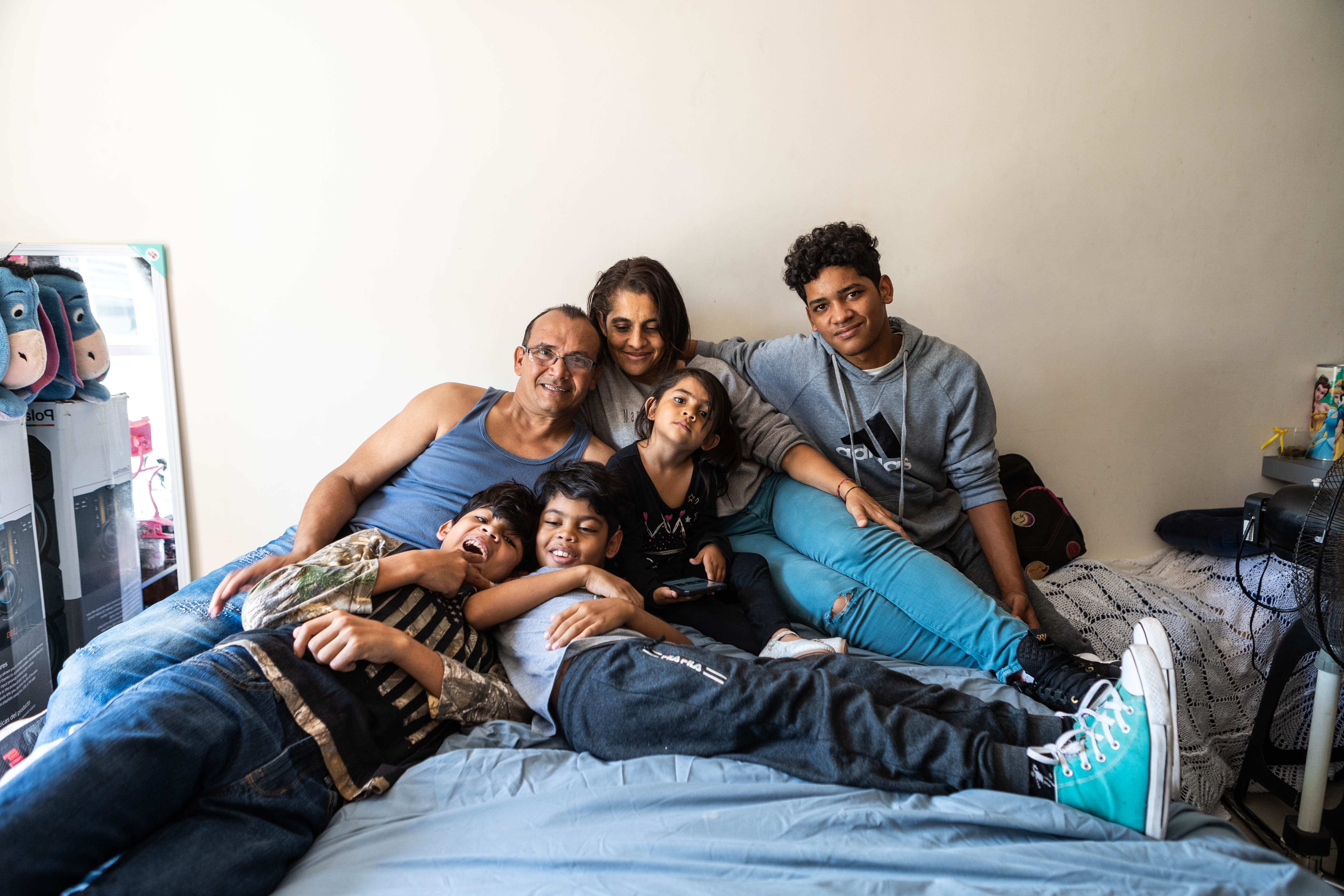 Allyson, her parents and three of her siblings pile onto a bed to take a family portrait.