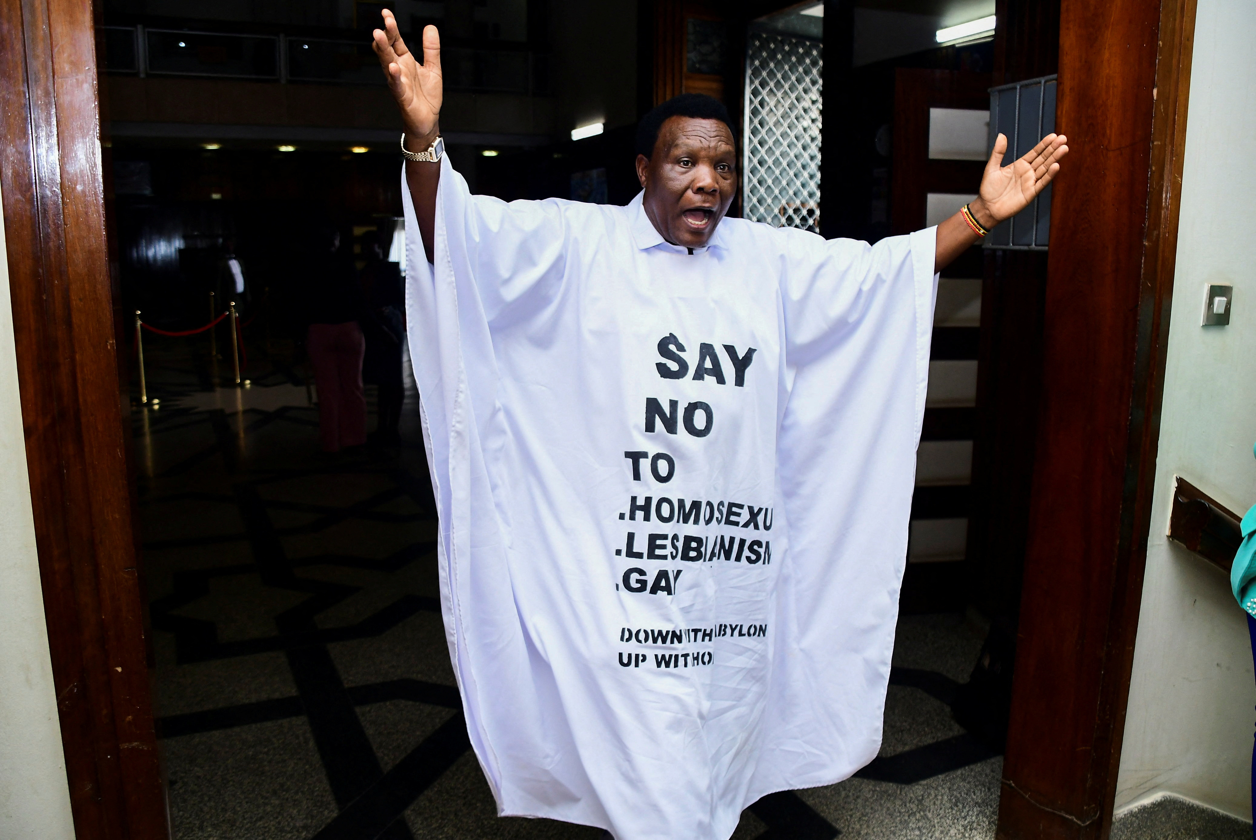 Member of Parliament from the Bubulo contituency John Musira dressed in an antigay gown gestures as he leaves the chambers during the debate of the Anti-Homosexuality bill, which proposes tough new penalties for same-sex relations during a sitting at the parliament buildings in Kampala, Uganda.