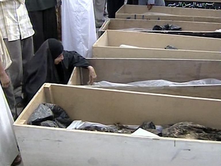 A woman grieves in front of coffins