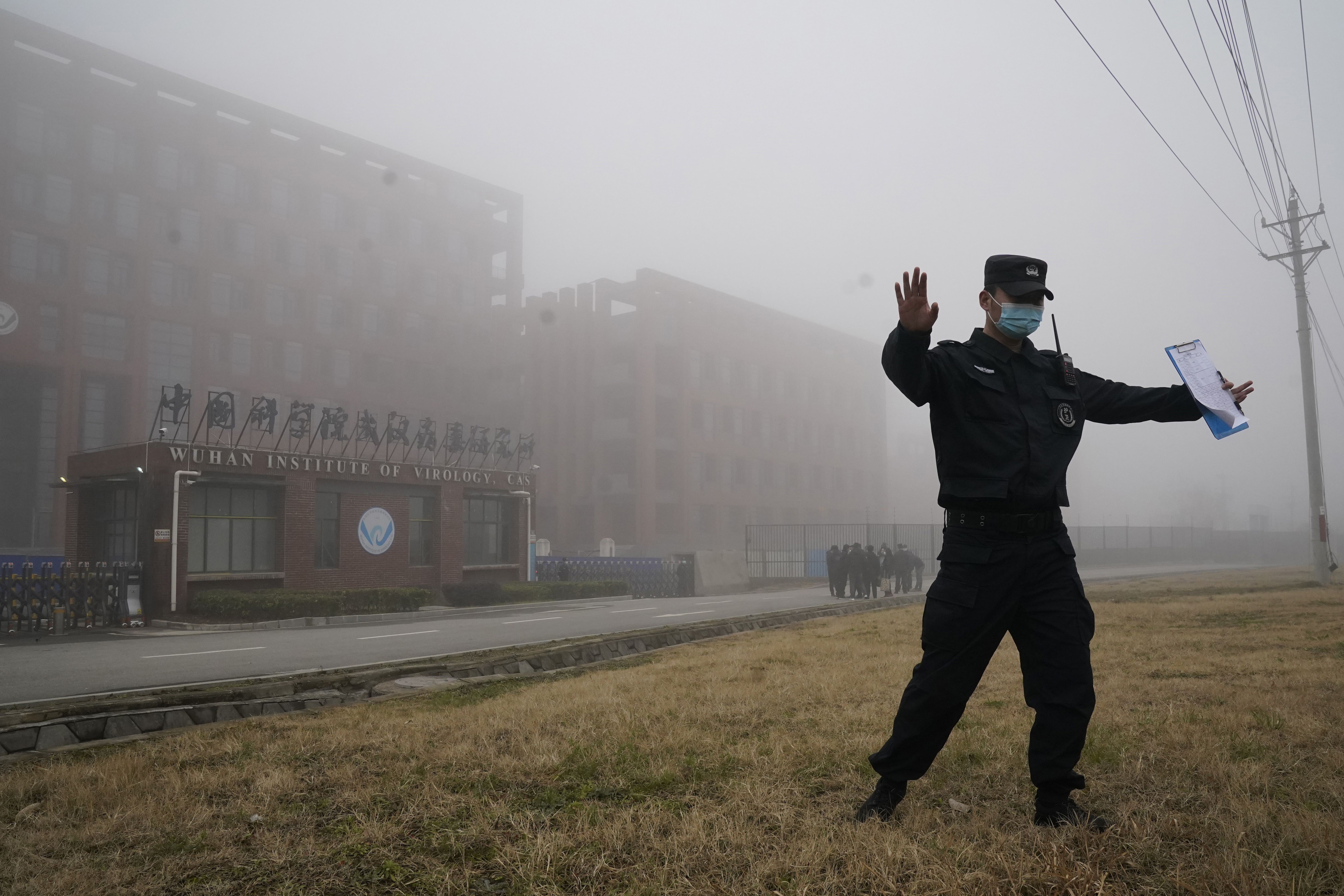 A security official moves journalists away from the Wuhan Institute of Virology after a World Health Organization team arrived for a field visit in Wuhan in China's Hubei province on Wednesday, Feb. 3, 2021. The WHO team is investigating the origins of the coronavirus pandemic has visited two disease control centers in the province. (AP Photo/Ng Han Guan)