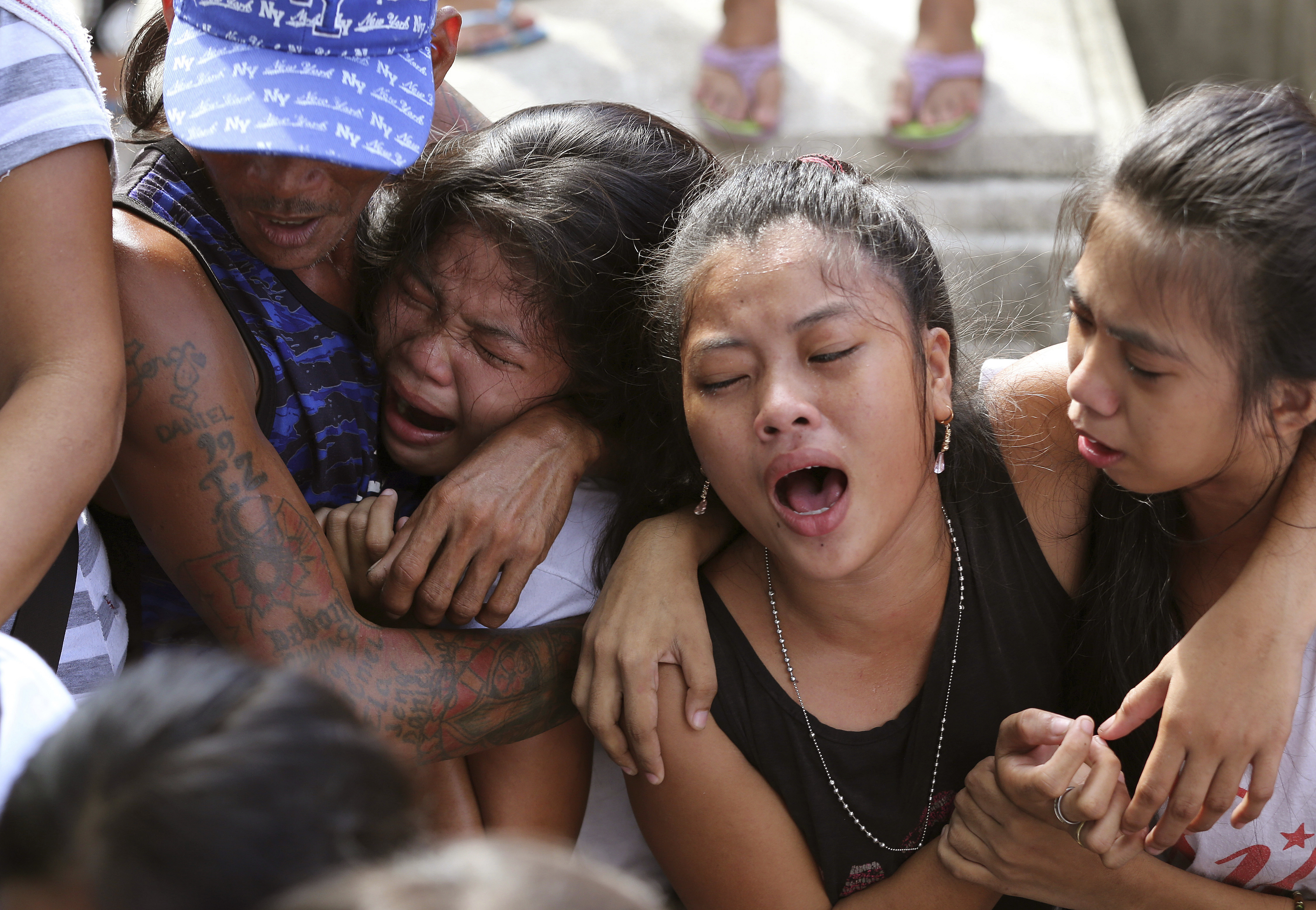 Distraught family and friends hug each other and cry at the funeral of a man killed by police as an alleged drug suspect.
