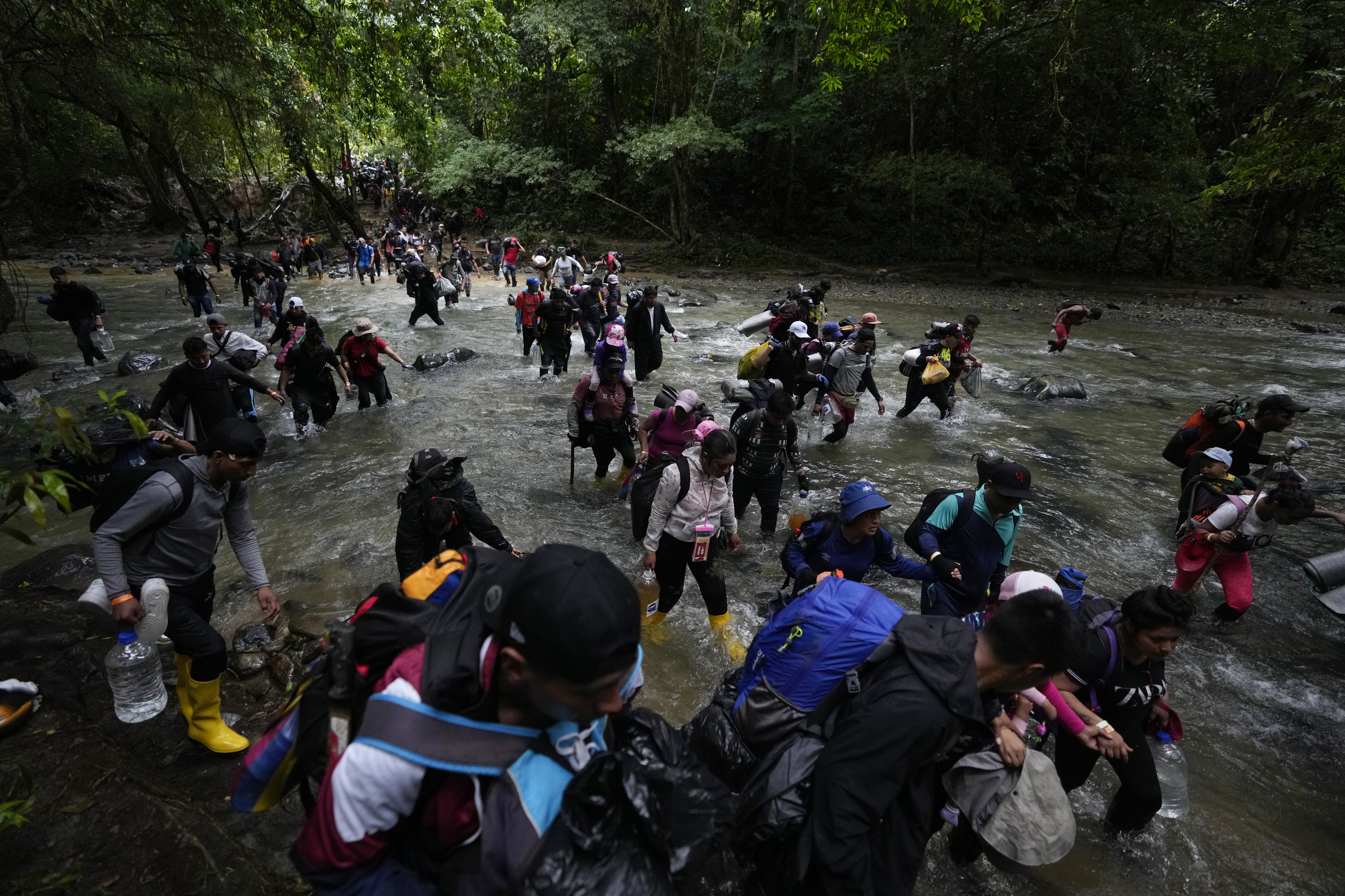 A group of migrants, mostly Venezuelans, cross a river during their journey through the Darien Gap from Colombia into Panama hoping to reach the U.S., Saturday, Oct. 15, 2022. (AP Photo/Fernando Vergara)