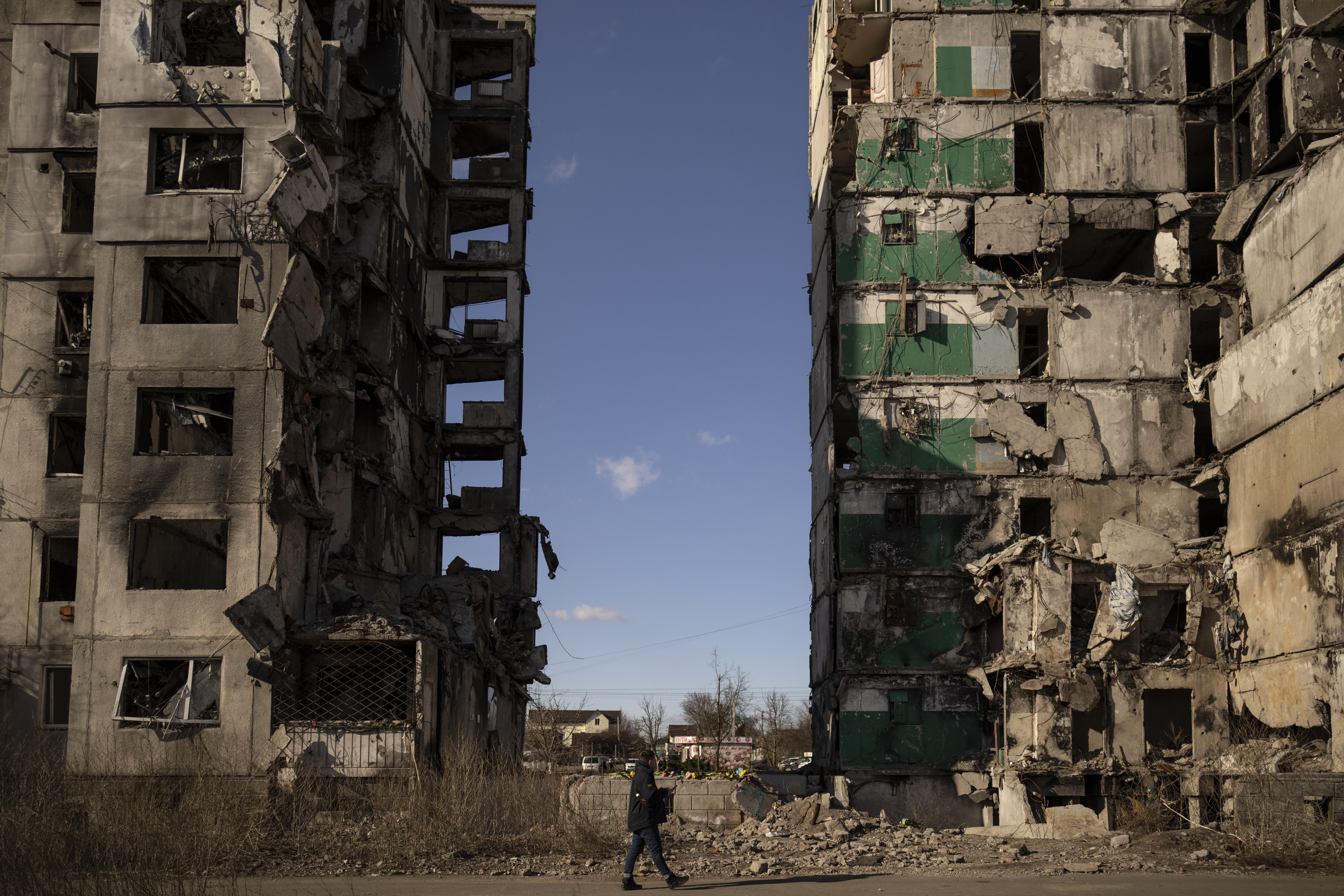 A man walks by an apartment block missing its central section after being hit by an airstrike, one year ago, in Borodyanka, Ukraine, Thursday, March 2, 2023. Nearly a year after towns and villages near Kyiv were retaken from Russian troops who had seized territory as they raced toward Kyiv at the start of their invasion of Ukraine, authorities are still exhuming the bodies of civilians hastily buried in makeshift graves. (AP Photo/Vadim Ghirda)
