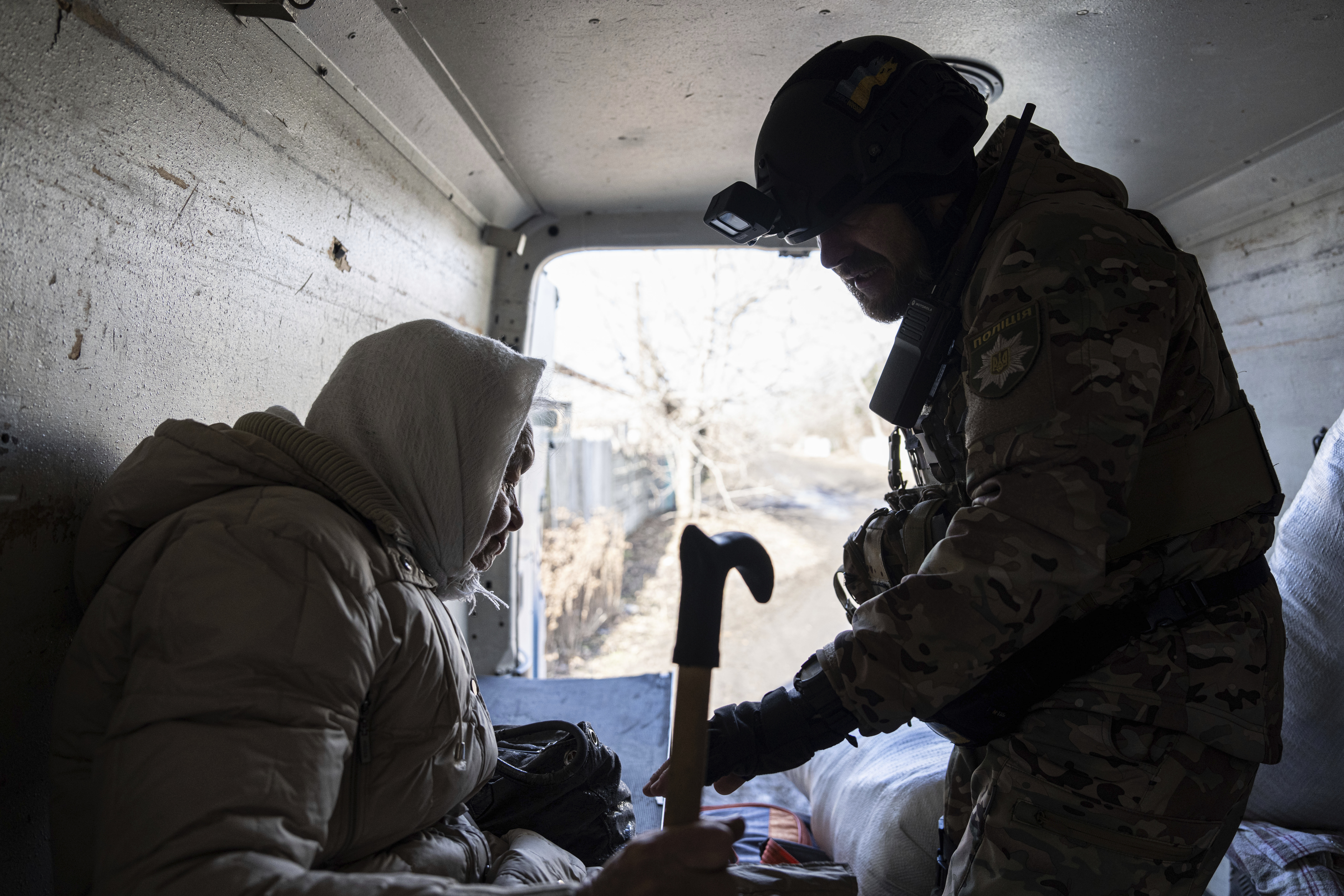 A Ukrainian police officer helps en elderly woman as she evacuates to safe areas in Chasiv Yar near Bakhmut