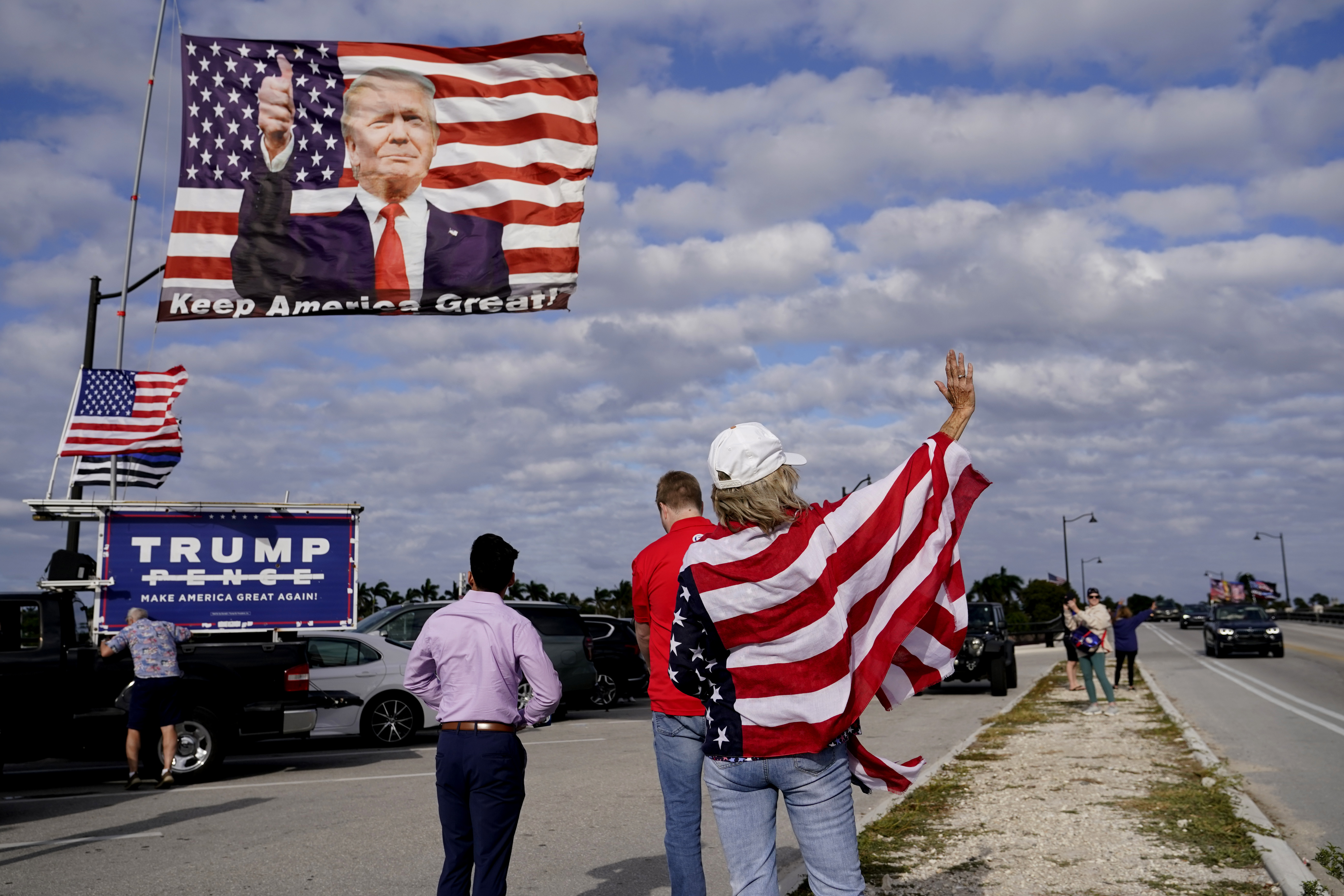 A supporter of former President Donald Trump waves to passersby outside of Trump's Mar-a-Lago estate in Palm Beach, Florida.