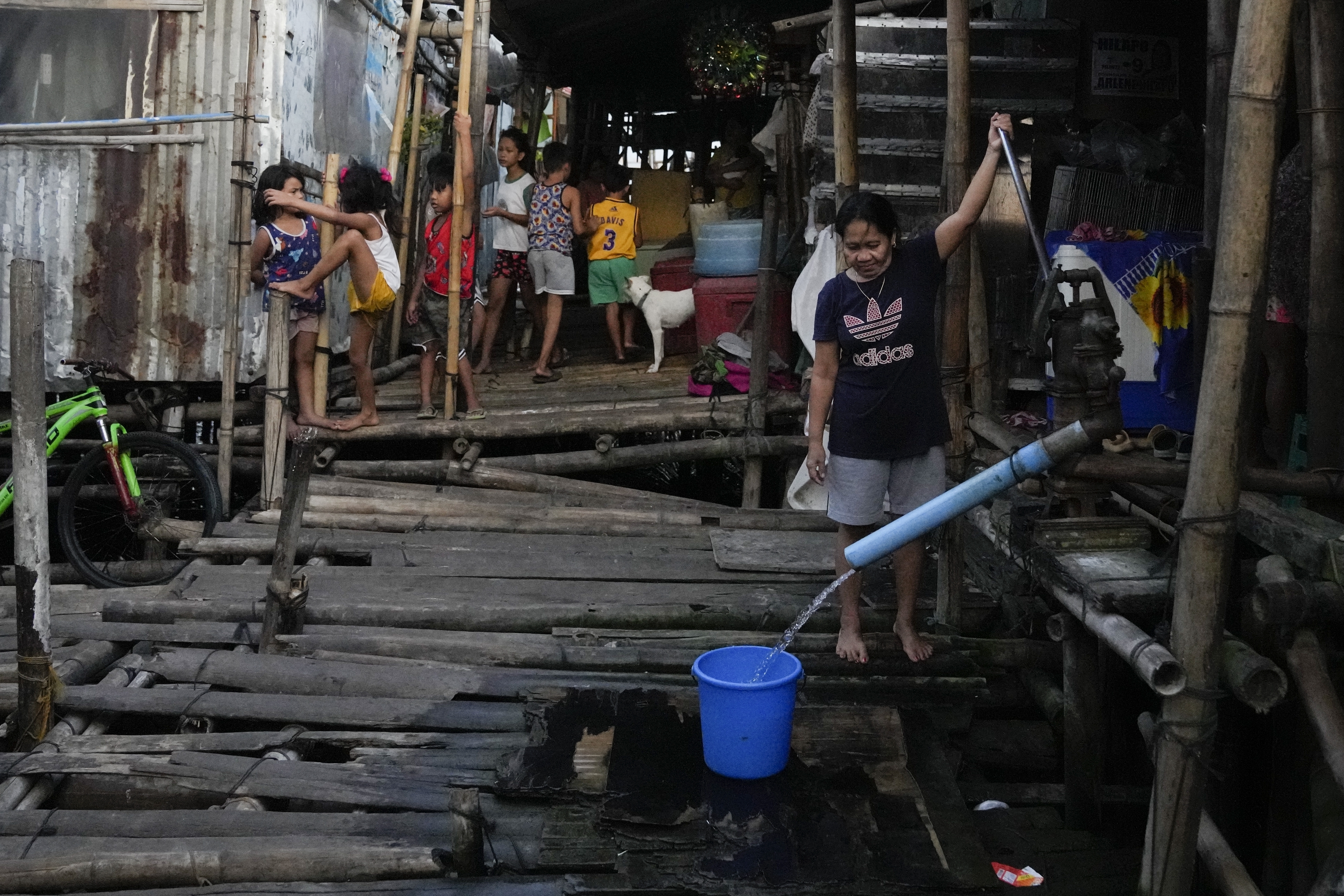 A woman uses a manual water pump at a slum area in Muntinlupa, Philippines