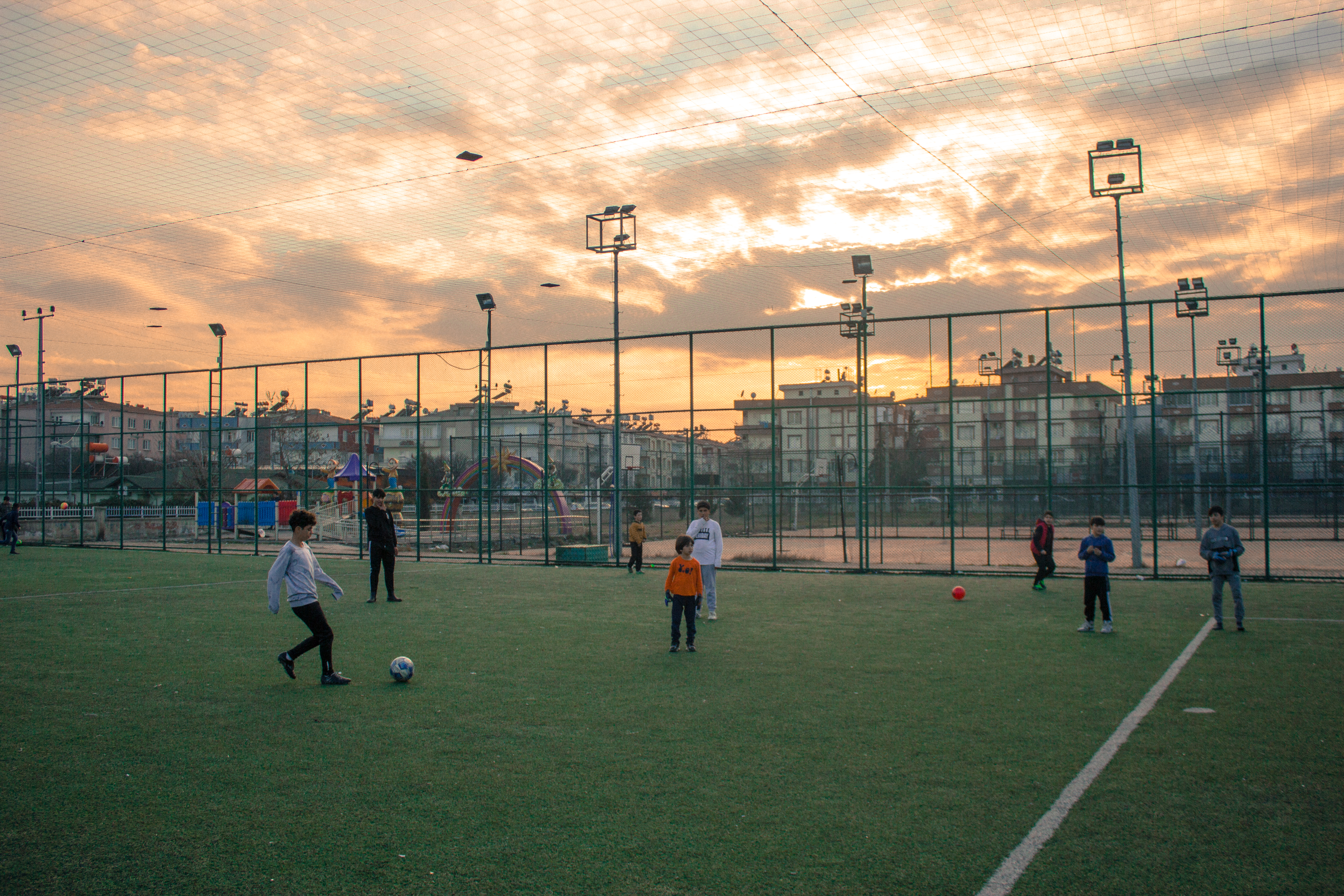 Kids play football on an outdoor pitch.
