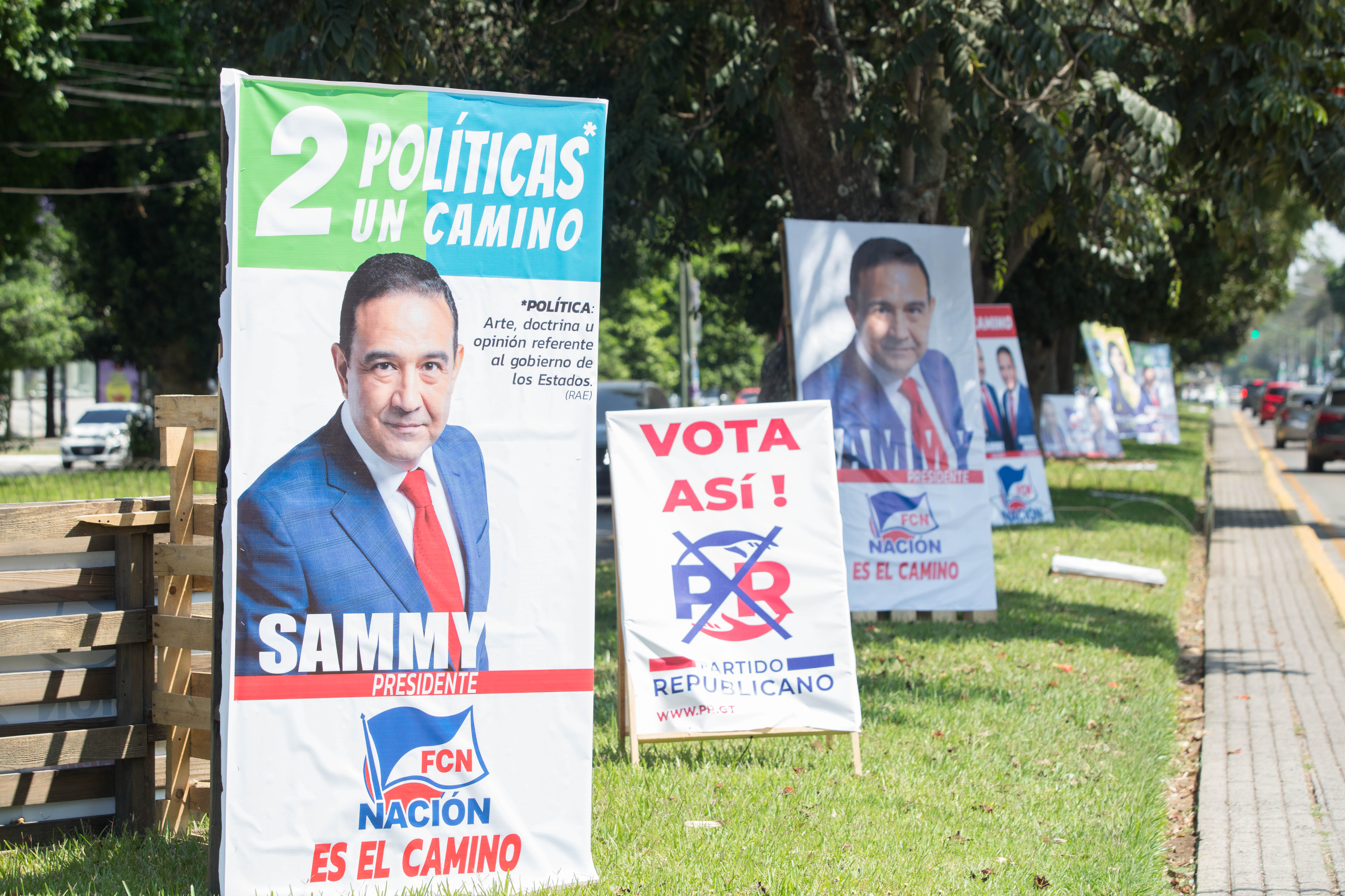 Campaign posters for various candidates line a street in Guatemala City