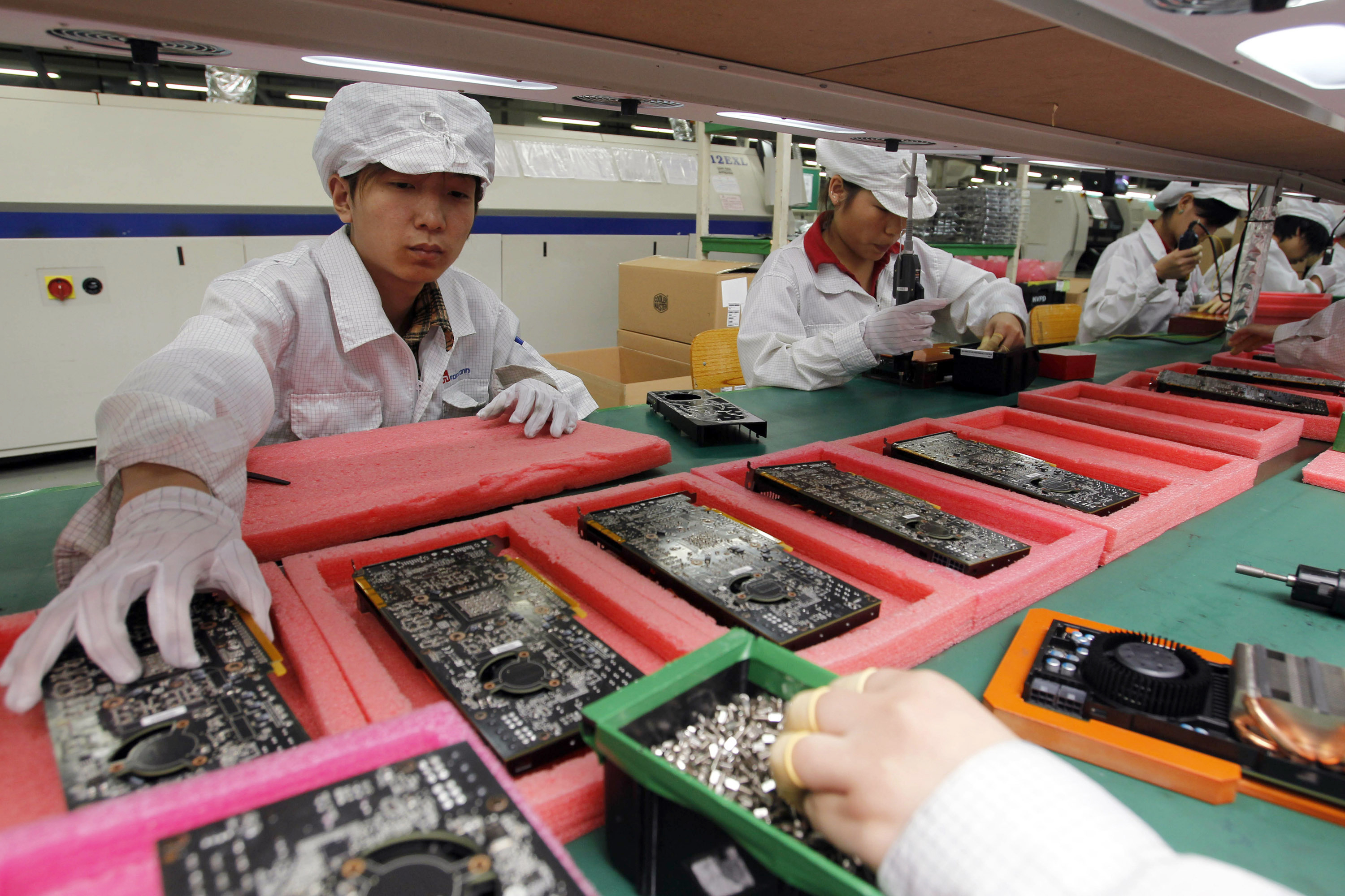 FILE - In this May 26, 2010 file photo, staff members work on the production line at the Foxconn complex in the southern Chinese city of Shenzhen, Southern city in China. Wisconsin Gov. Scott Walker says President Donald Trump plans to make a "major jobs announcement for Wisconsin" as anticipation builds it will be about electronics giant Foxconn locating in the state. Taiwan-based Foxconn is best known as the assembler of the iPhone. Wisconsin is among seven states, mostly in the Midwest, that the company has named as possible locations to build the its first liquid-crystal display factory that could mean tens of thousands of jobs. (AP Photo/Kin Cheung, File)