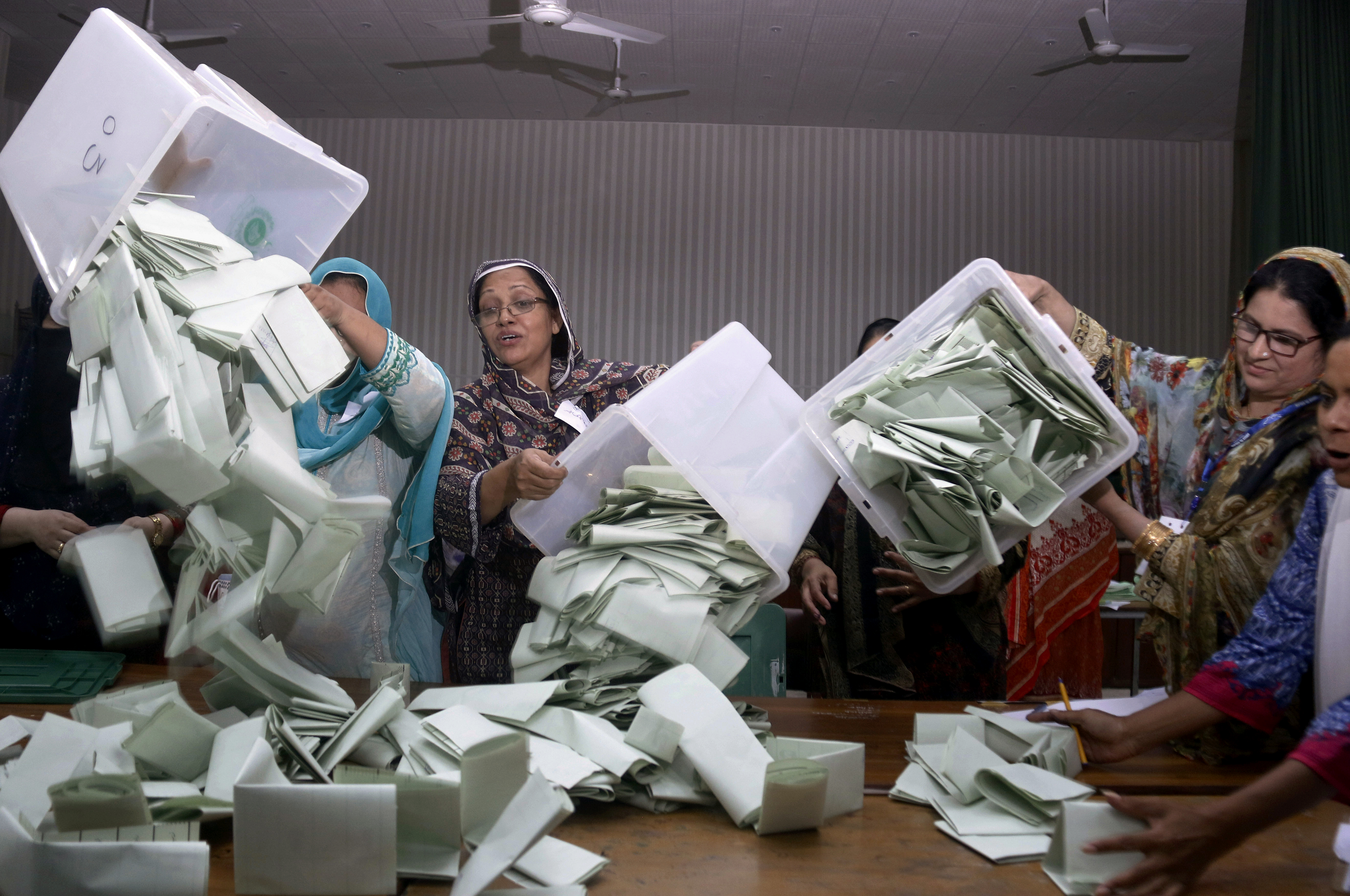 Pakistani election staff empty the ballot boxes to start counting following polls closed at a polling station for the parliamentary elections in Islamabad, Pakistan