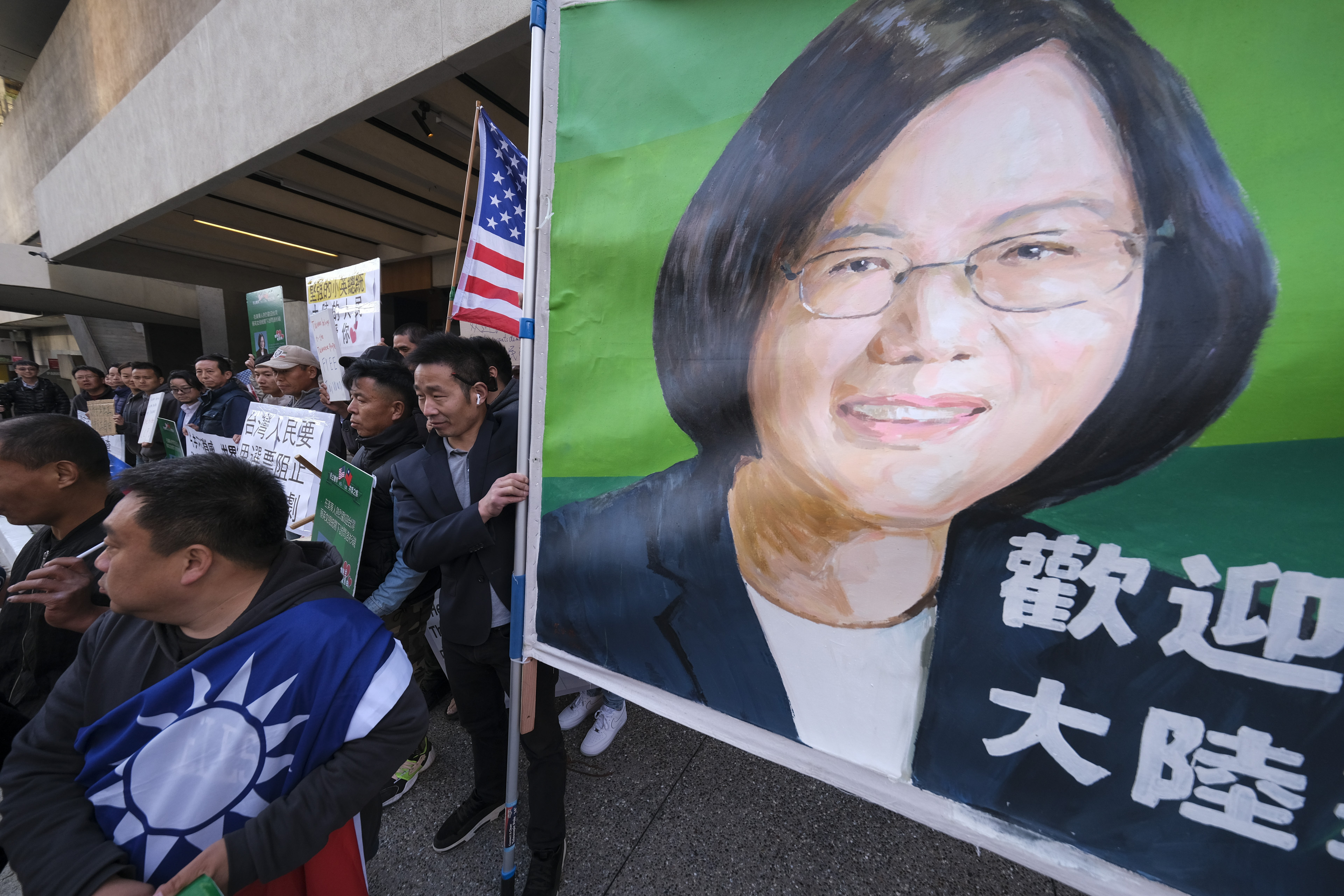 People carry American and Taiwan flags along with a large poster of Tsai Ing-wen's face