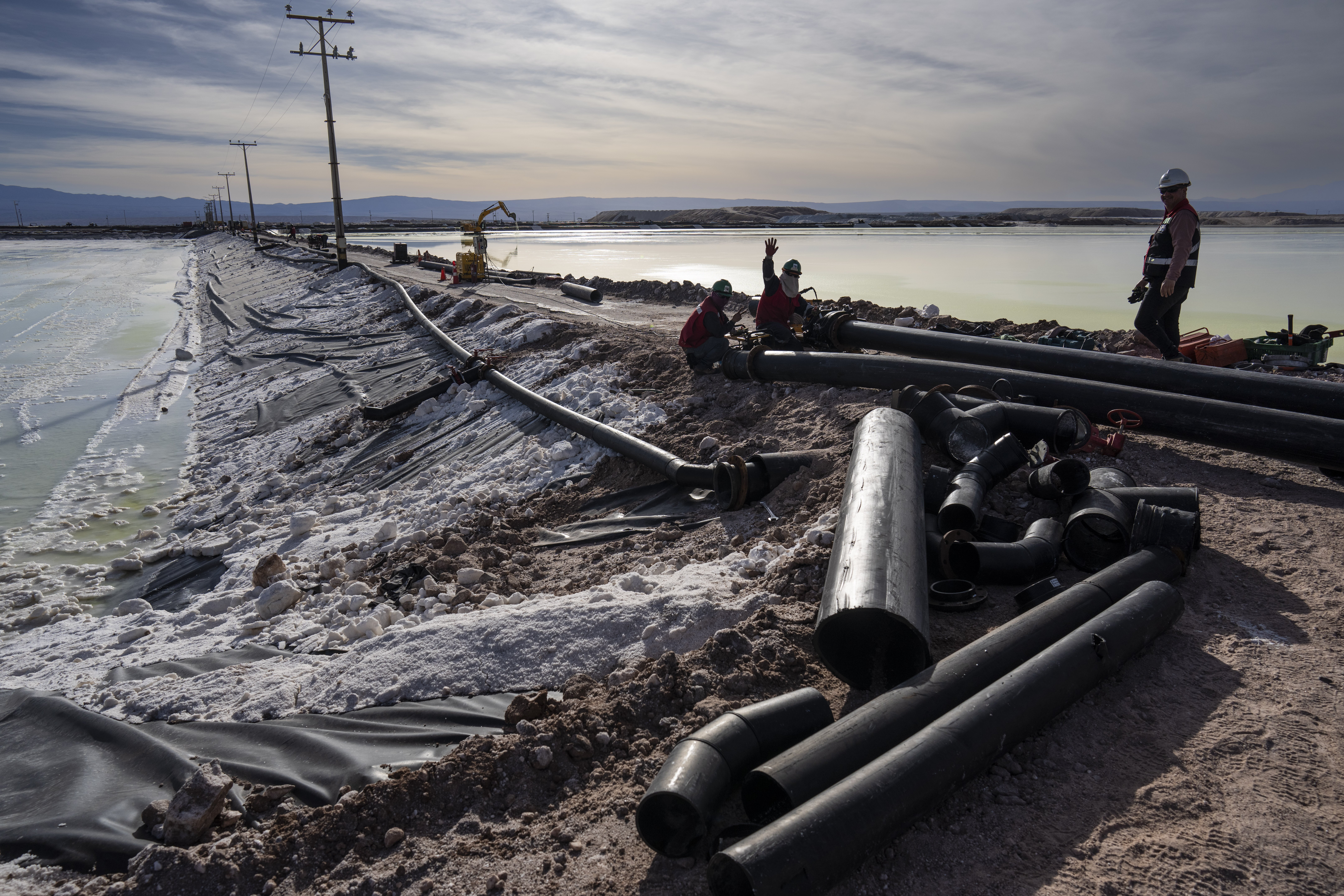 Workers perform maintenance next to pools of brine slowly turning into lithium at the SQM mine in Chile's Atacama desert