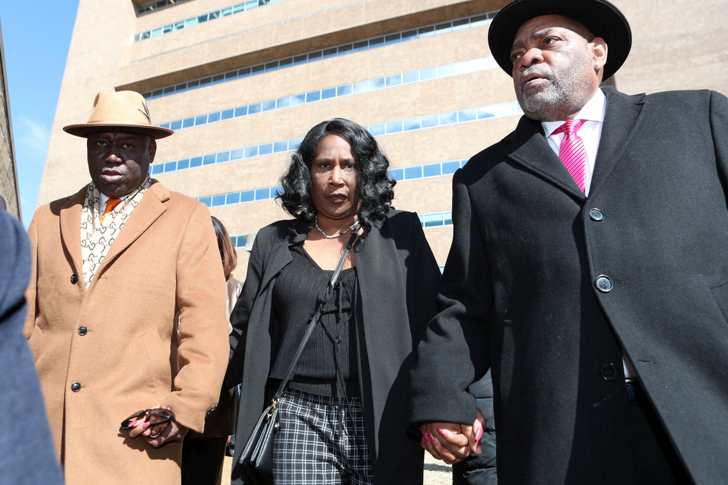 Three people walk away from a courthouse, holding hands