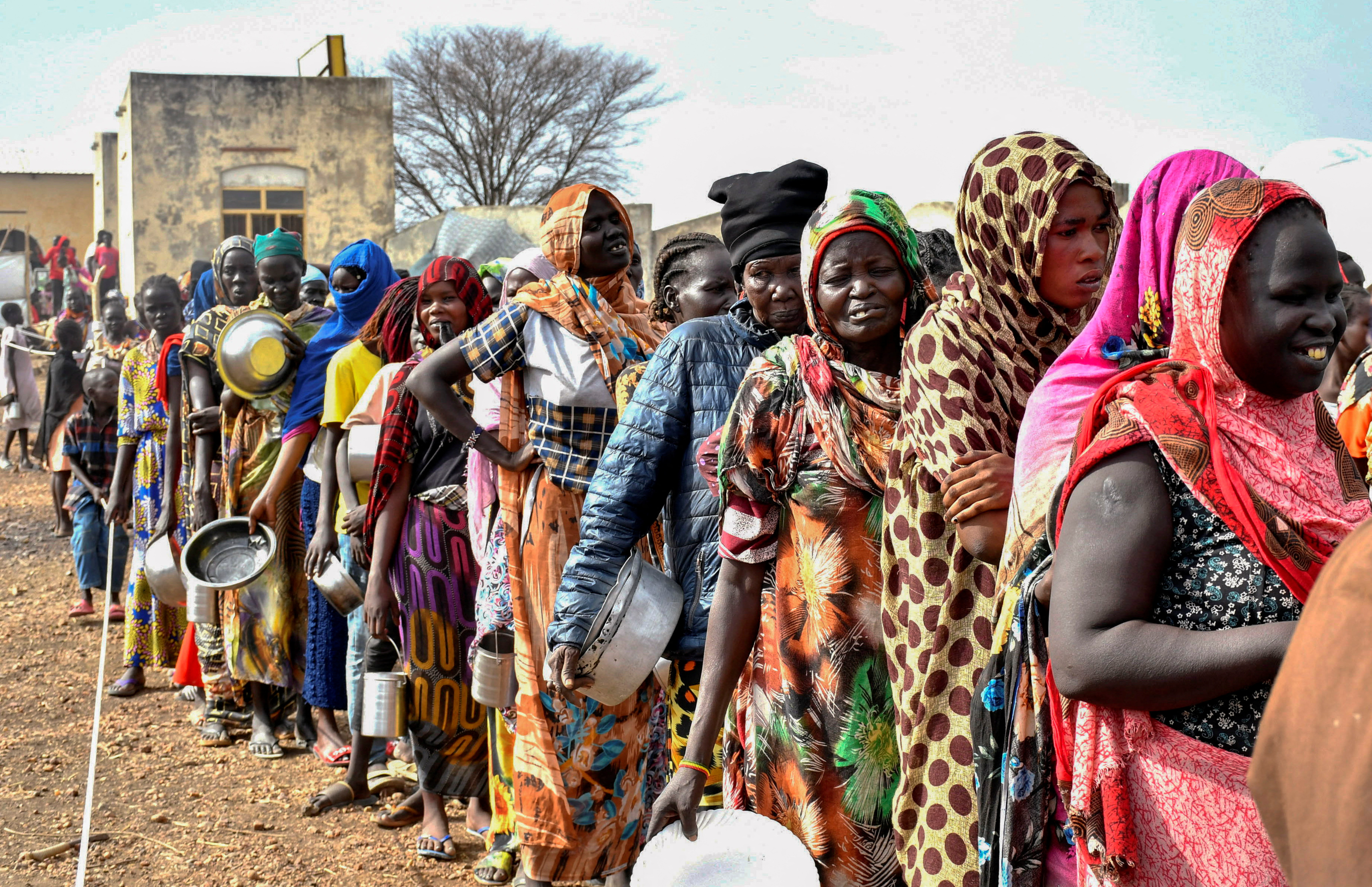 Women who fled the war-torn Sudan following the outbreak of fighting between the Sudanese army and the paramilitary Rapid Support Forces (RSF) queue to receive food rations at the United Nations High Commissioner for Refugees (UNHCR) transit centre in Renk, near the border crossing point in Renk County of Upper Nile State, South Sudan