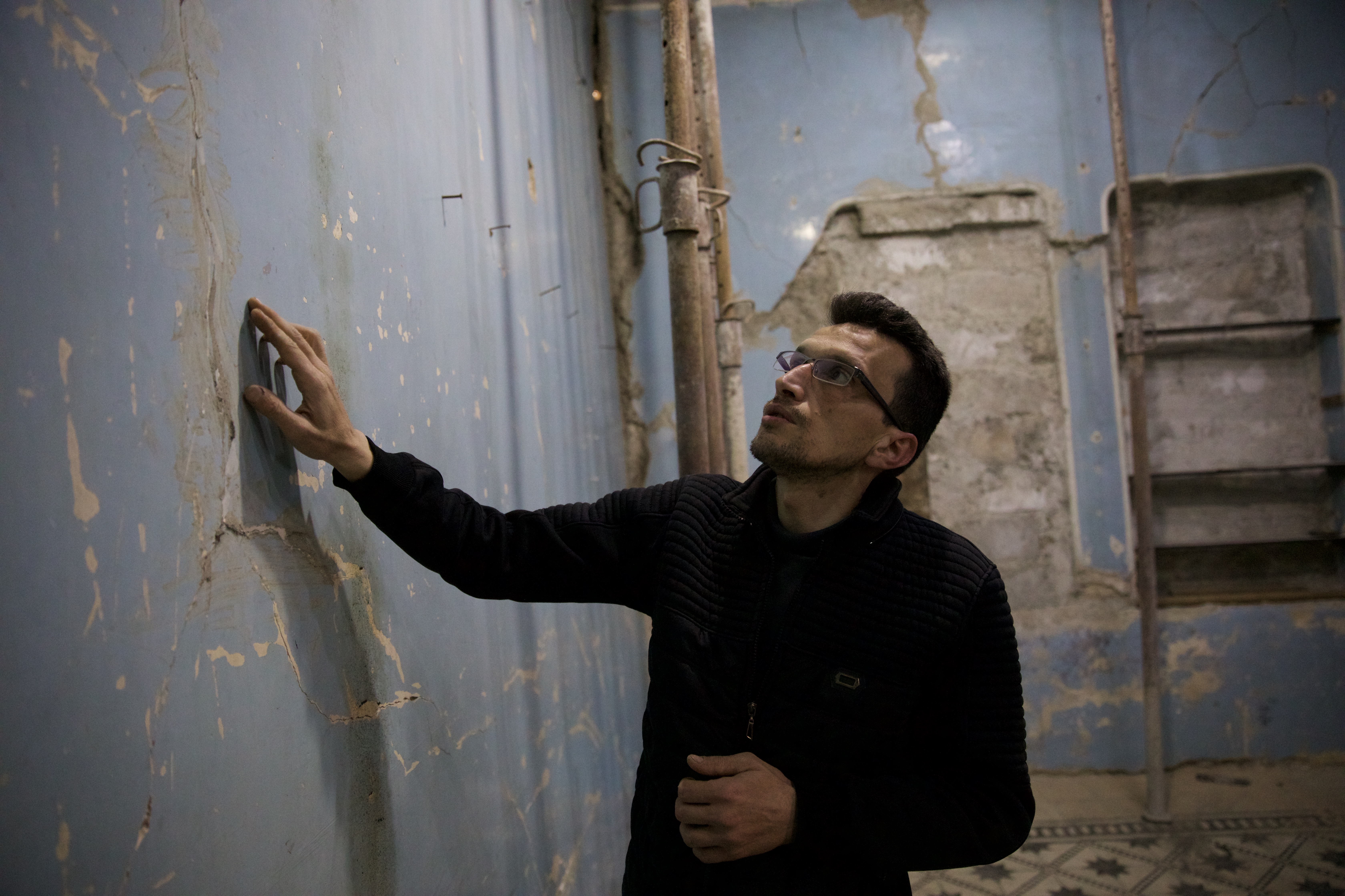 Man points to a cracked wall