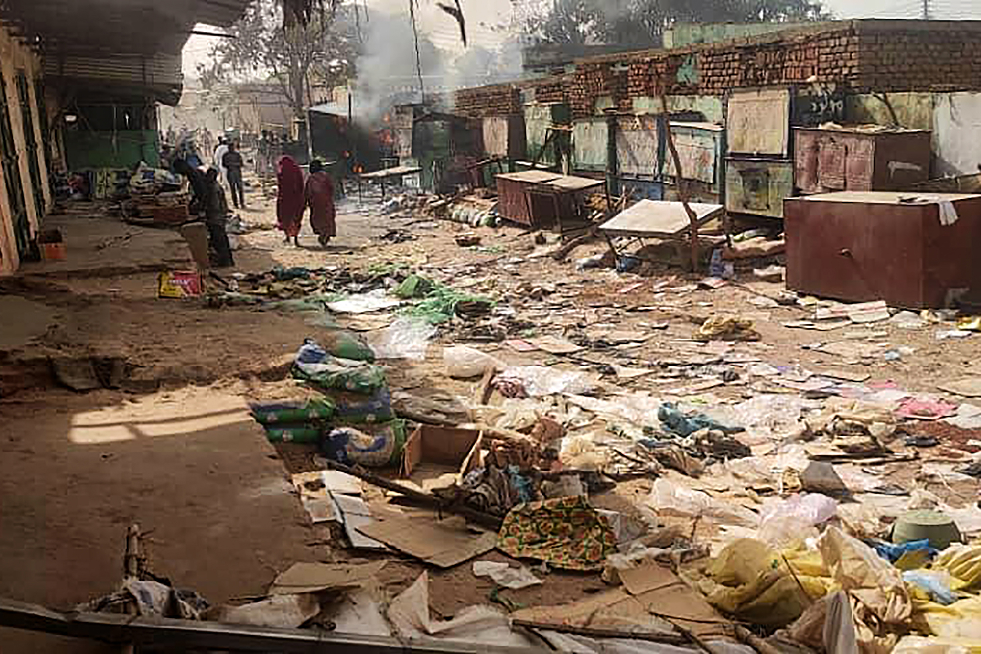 People walk among scattered objects in the market of El Geneina, the capital of West Darfur, as fighting continues in Sudan