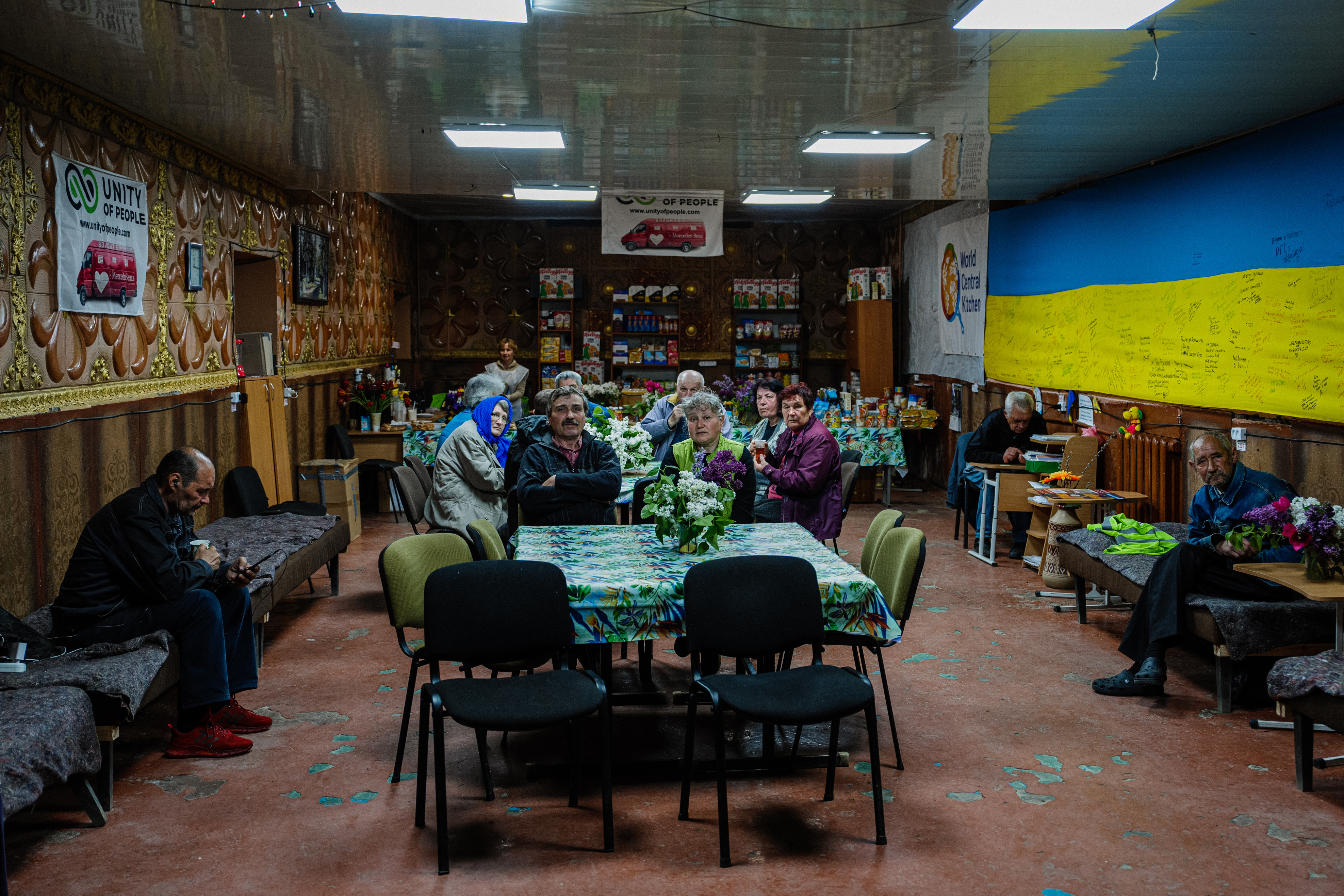 Local residents sit in a volunteer run shelter, providing access to laundry and bathroom facilities where they can warm up, charge their phones, drink hot tea and receive humanitarian aid in the town of Orikhiv, in the Zaporizhzhia region