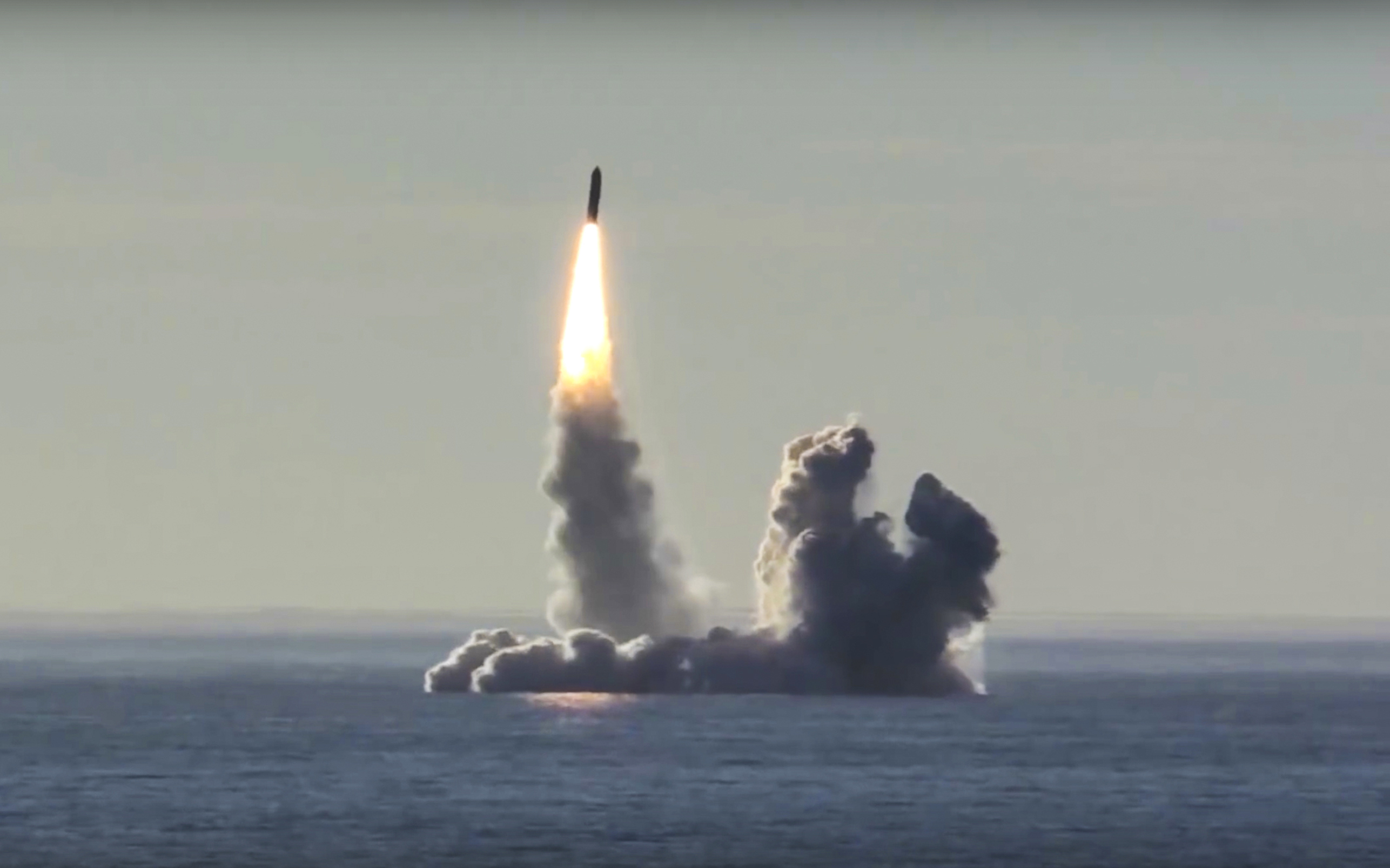 A bulava missile being tested from a Russian submarine. It is rising vertically leaving clouds of black smoke