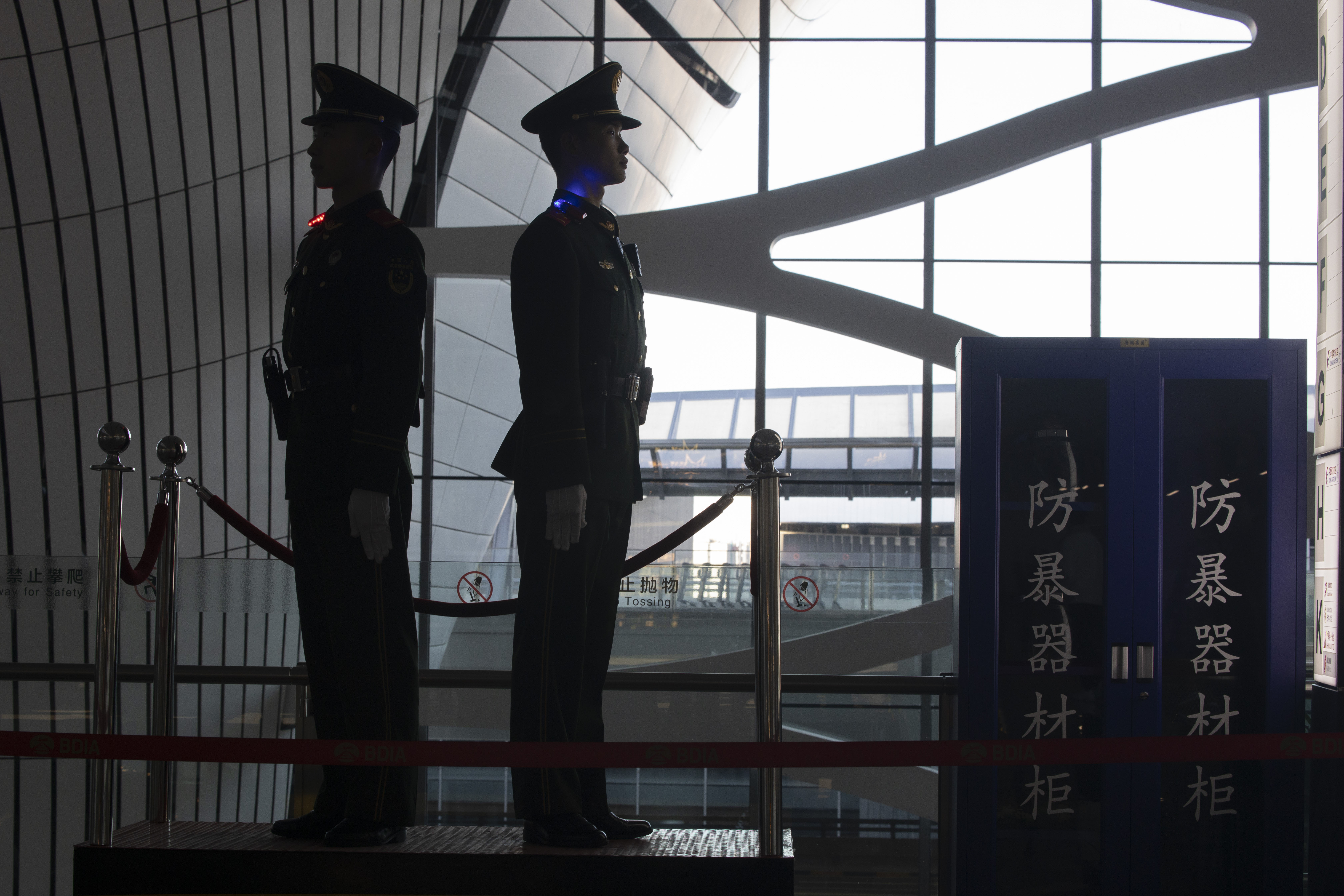 Paramilitary police at the Beijing airport. They are silhouetted against a large window.