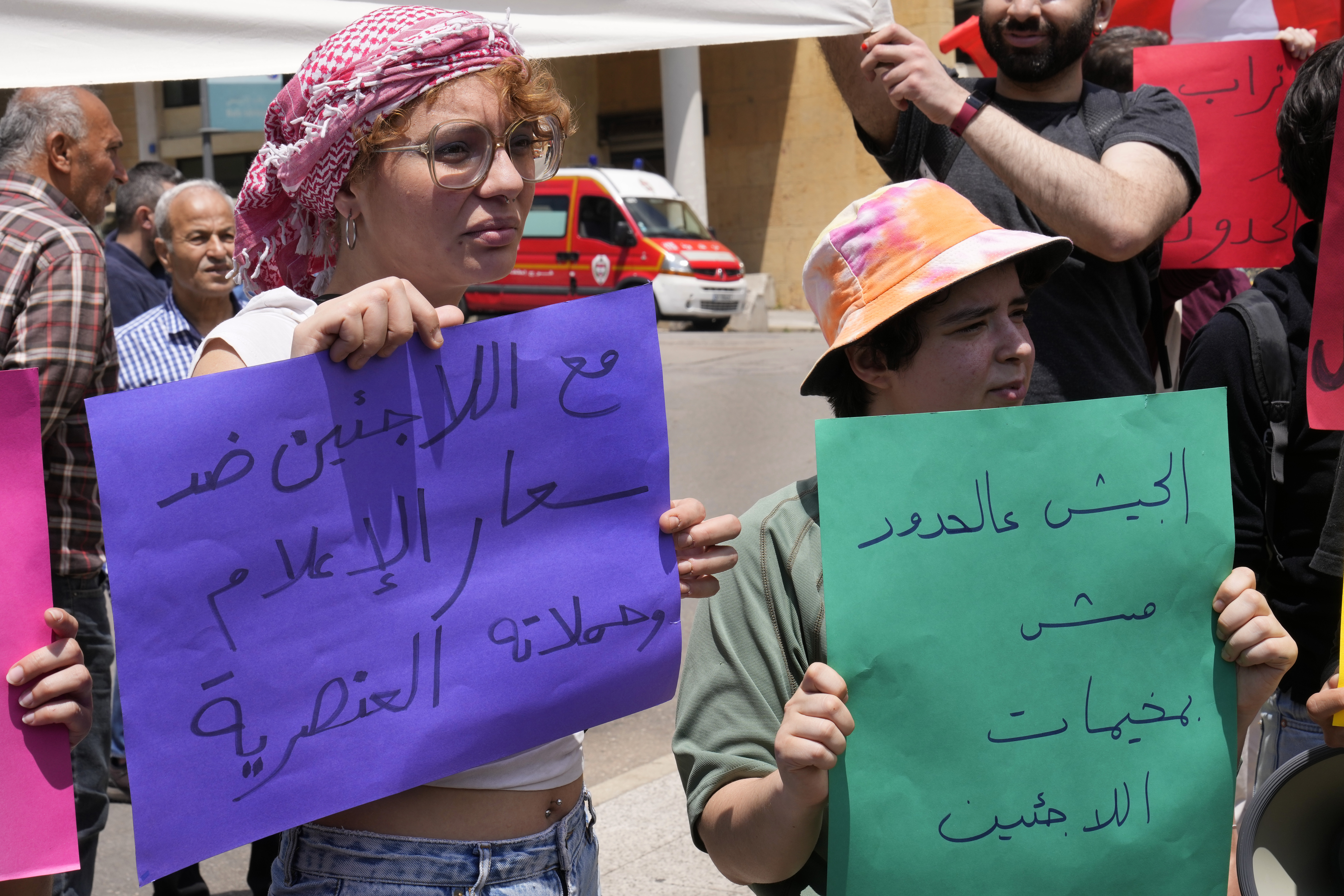 Protesters hold signs reading "With the refugees against the media frenzy and racist campaigns" and "The army's place is on the borders, not in the refugee camps" in Arabic at a workers' day march held by leftist groups in Beirut, Lebanon, Monday, May 1, 2023.