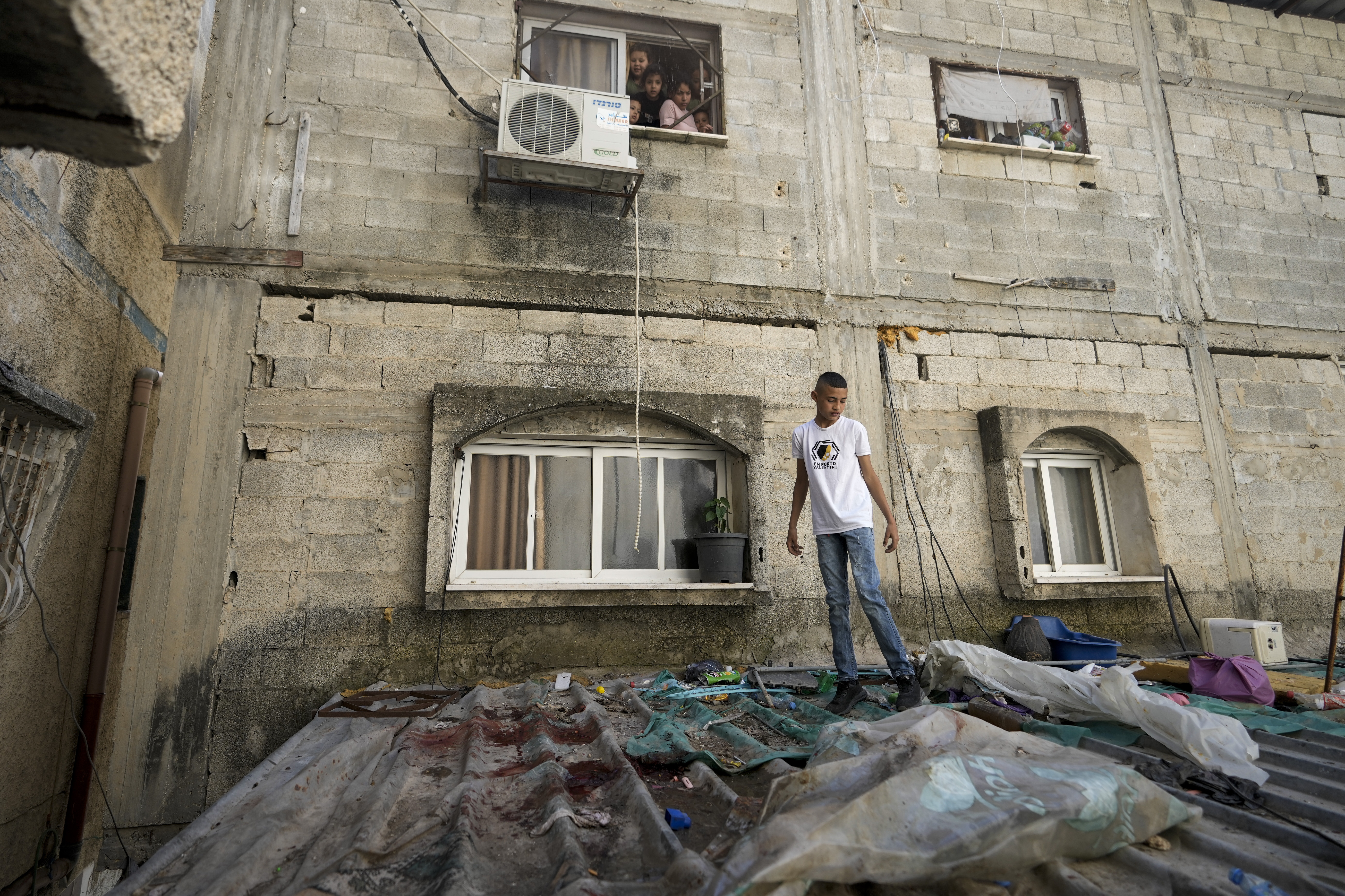 A boy looks at blood stains after a military raid in the Nur Shams refugee camp near the city of Tulkarem, in the occupied West Bank Saturday, May 6, 2023.