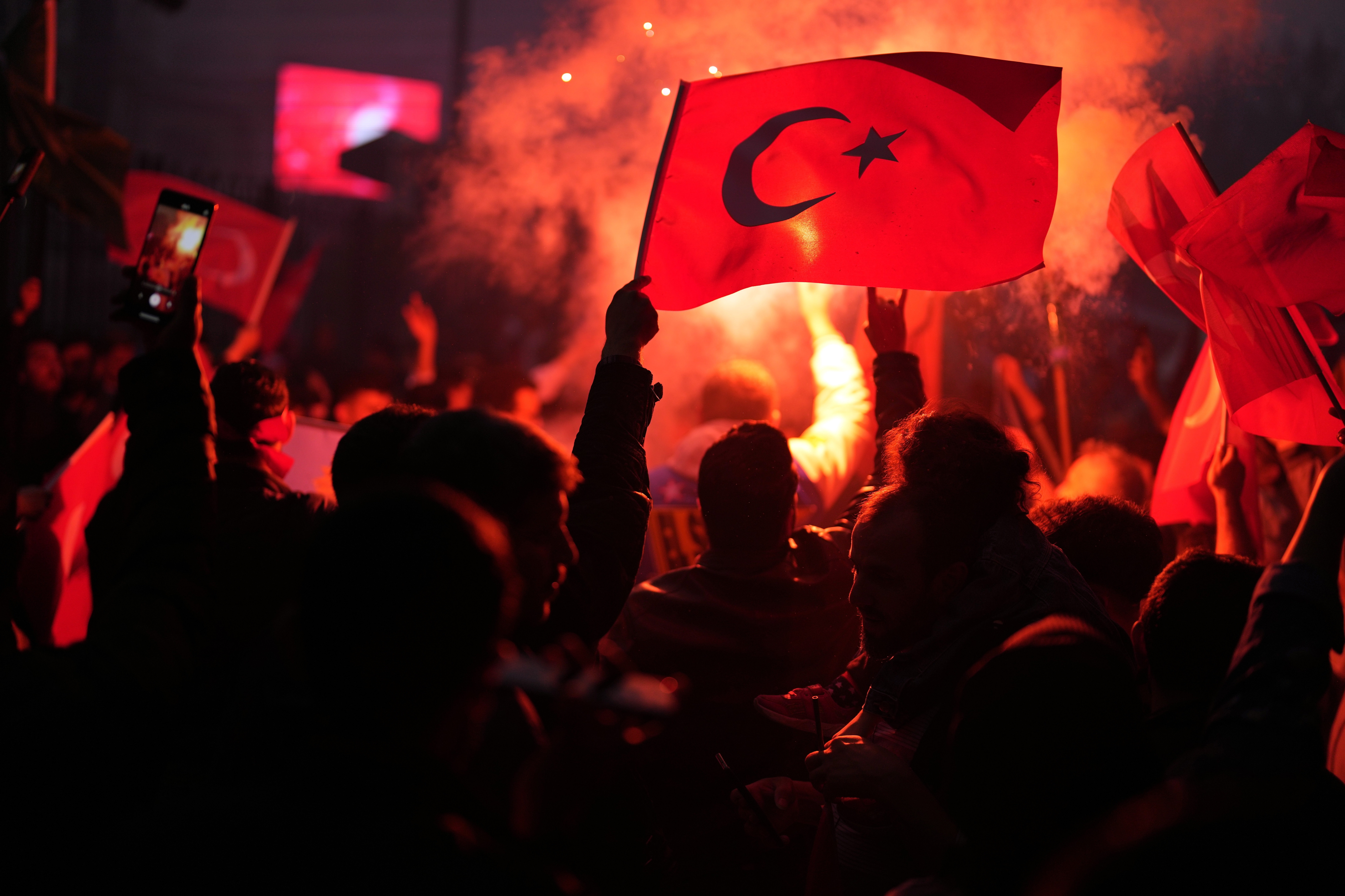 Supporters of the President Recep Tayyip Erdogan celebrate and wave a Turkish flag.