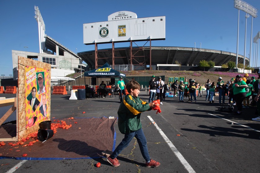 Oakland A fans throw tomatoes at a picture of owner John Fisher