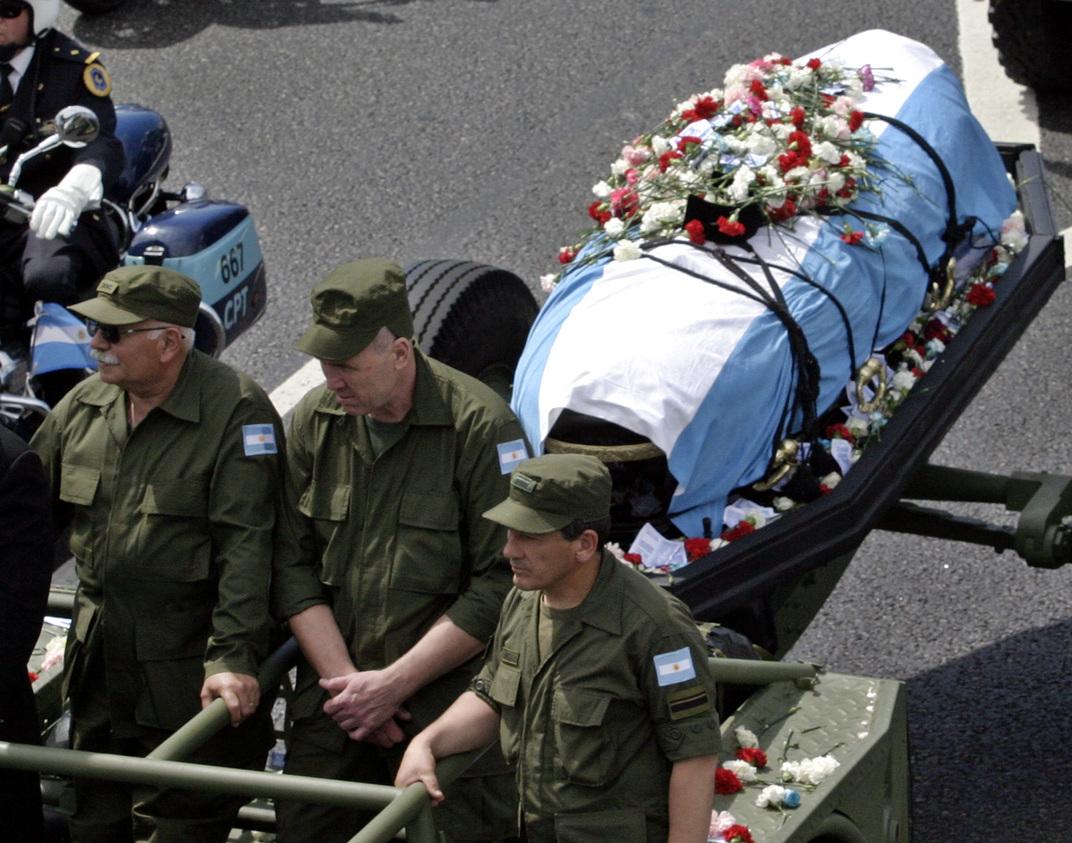 Military officials in a truck tow a coffin covered with the Argentine flag through the streets.