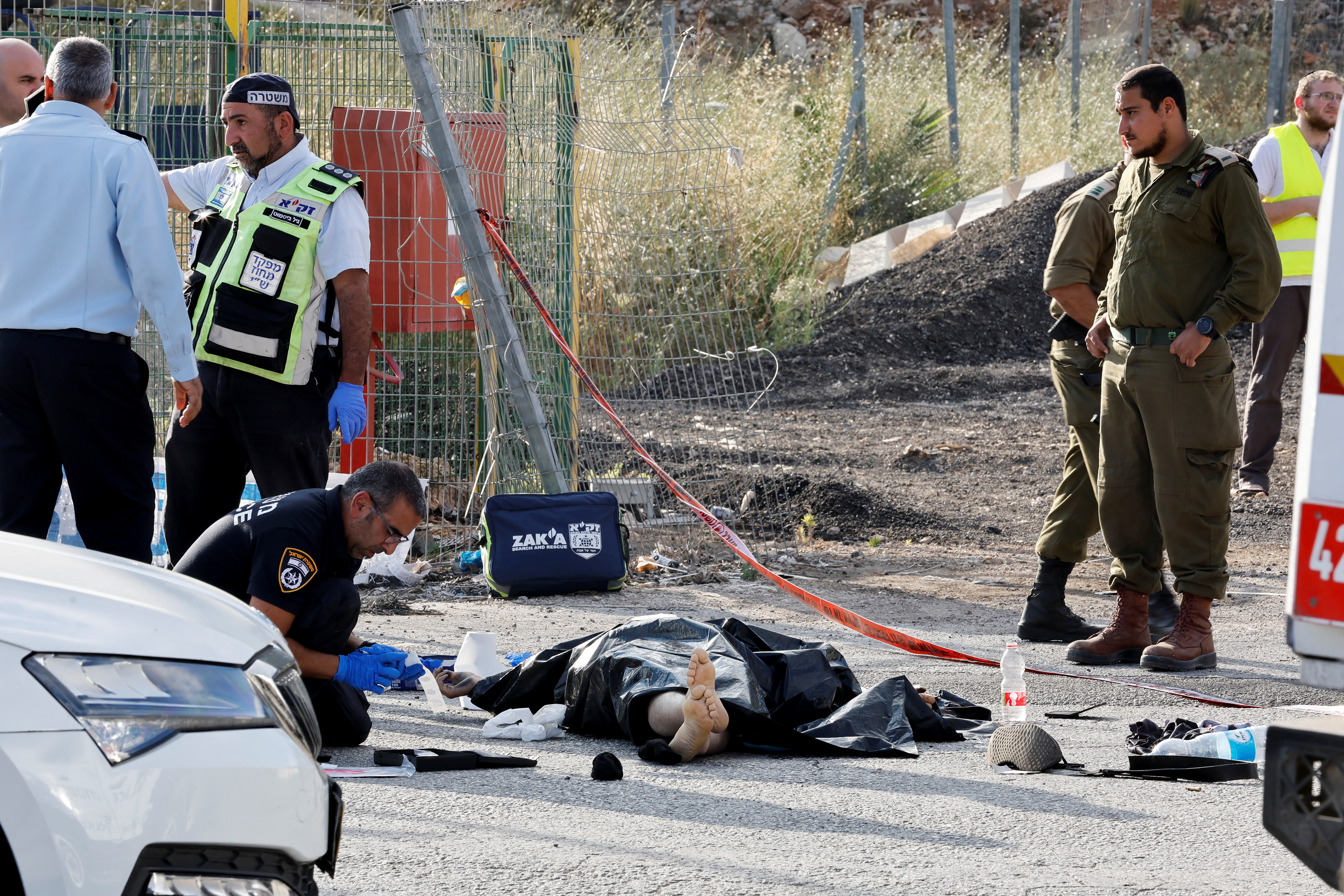 Security personnel work at the scene of a suspected Palestinian shooting attack that killed four people near the Jewish settlement of El
