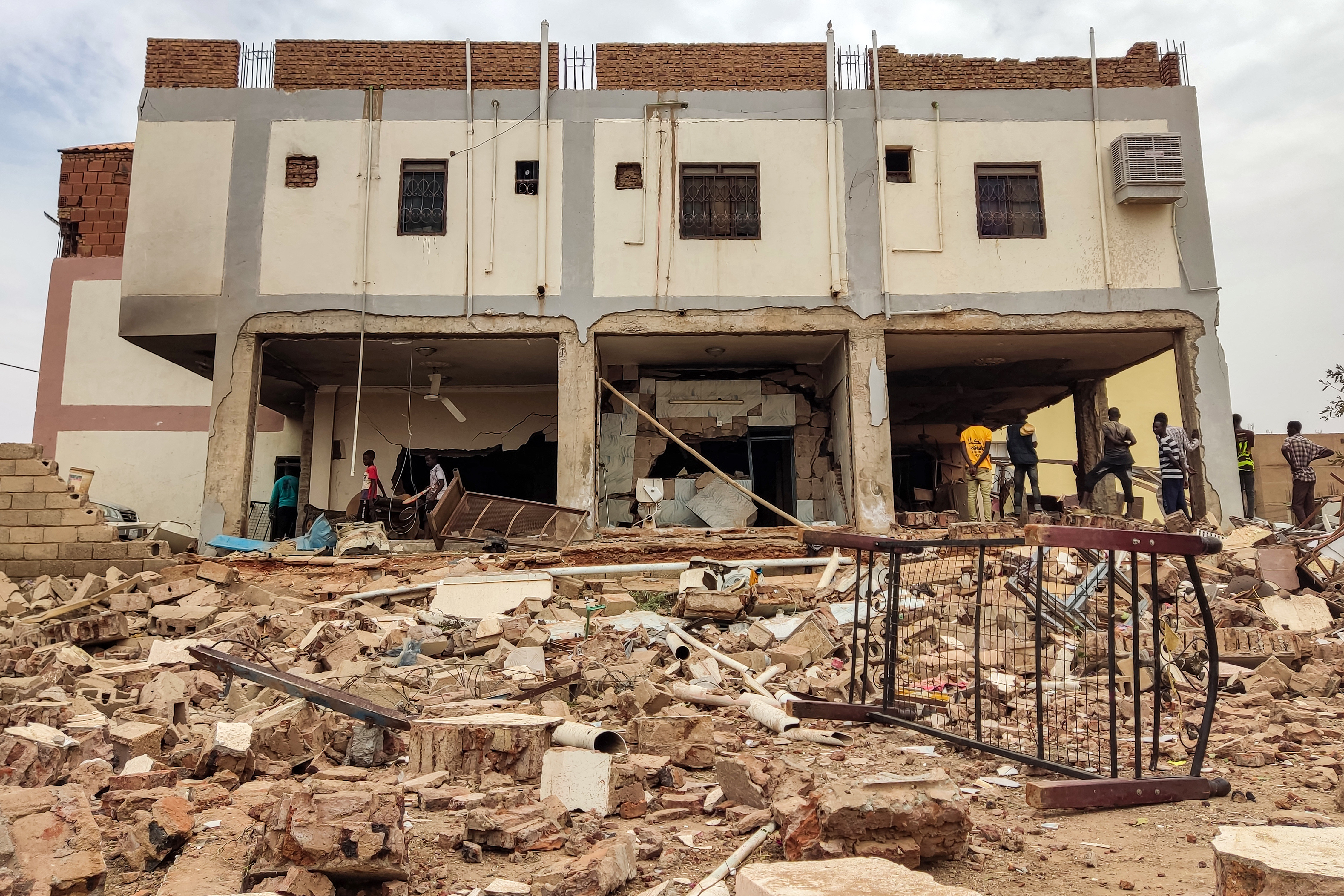People inspect the rubble at a house that was hit by an artillery shell in the
