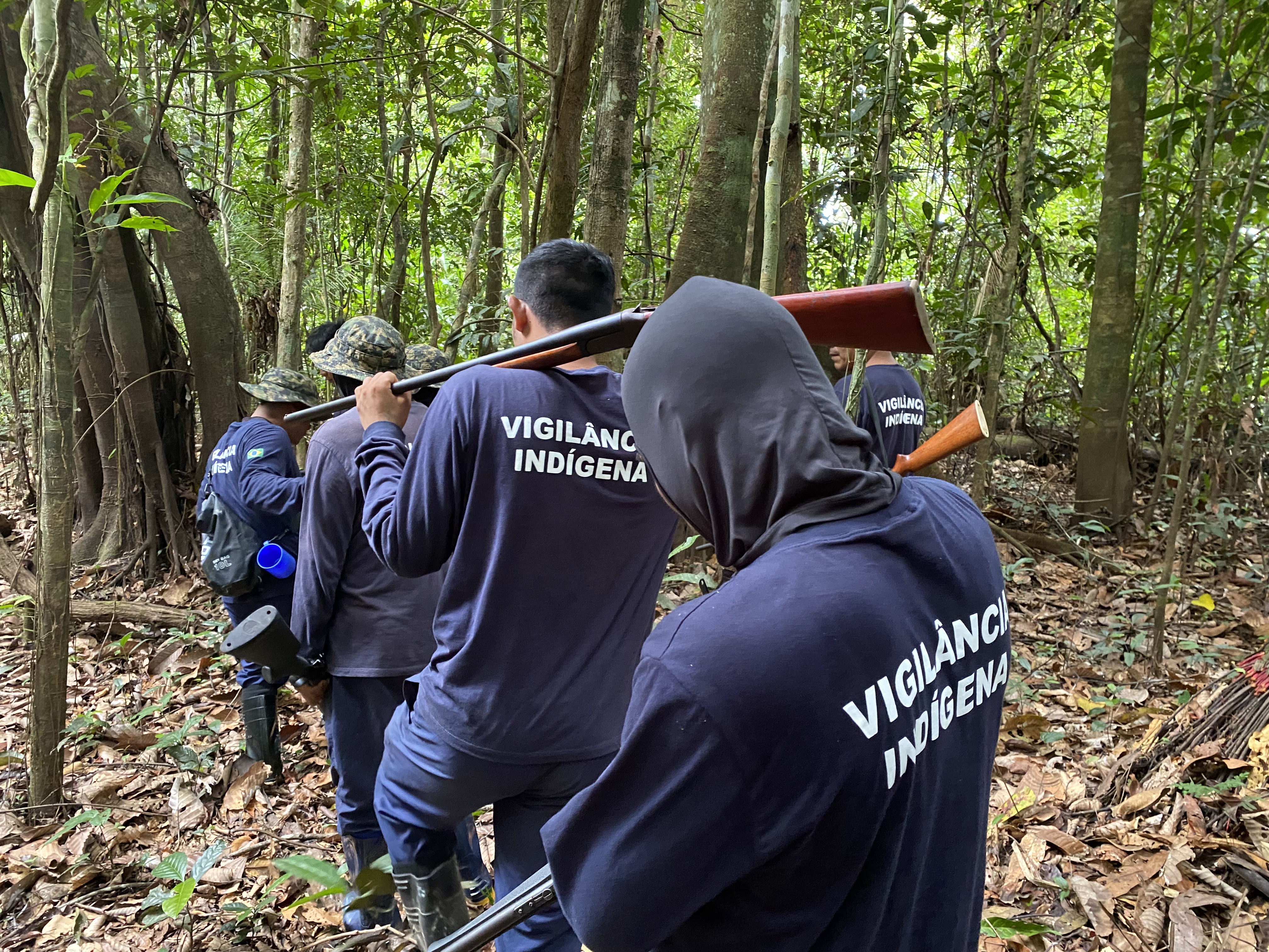 Indigenous members of a patrol team walk through a forested area in the Javari Valley, Brazil