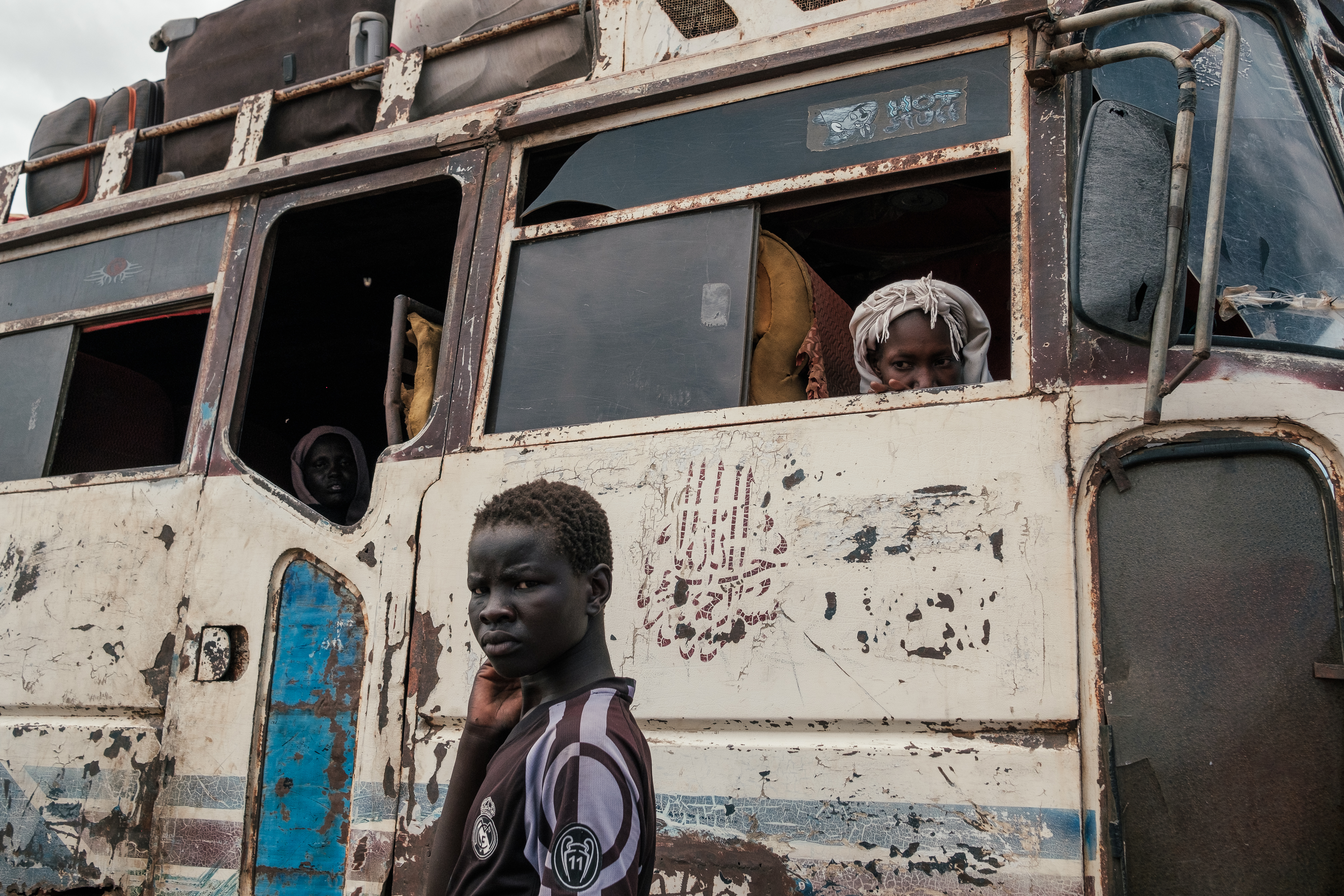 People wait as a bus is loaded outside the Renk transit centre
