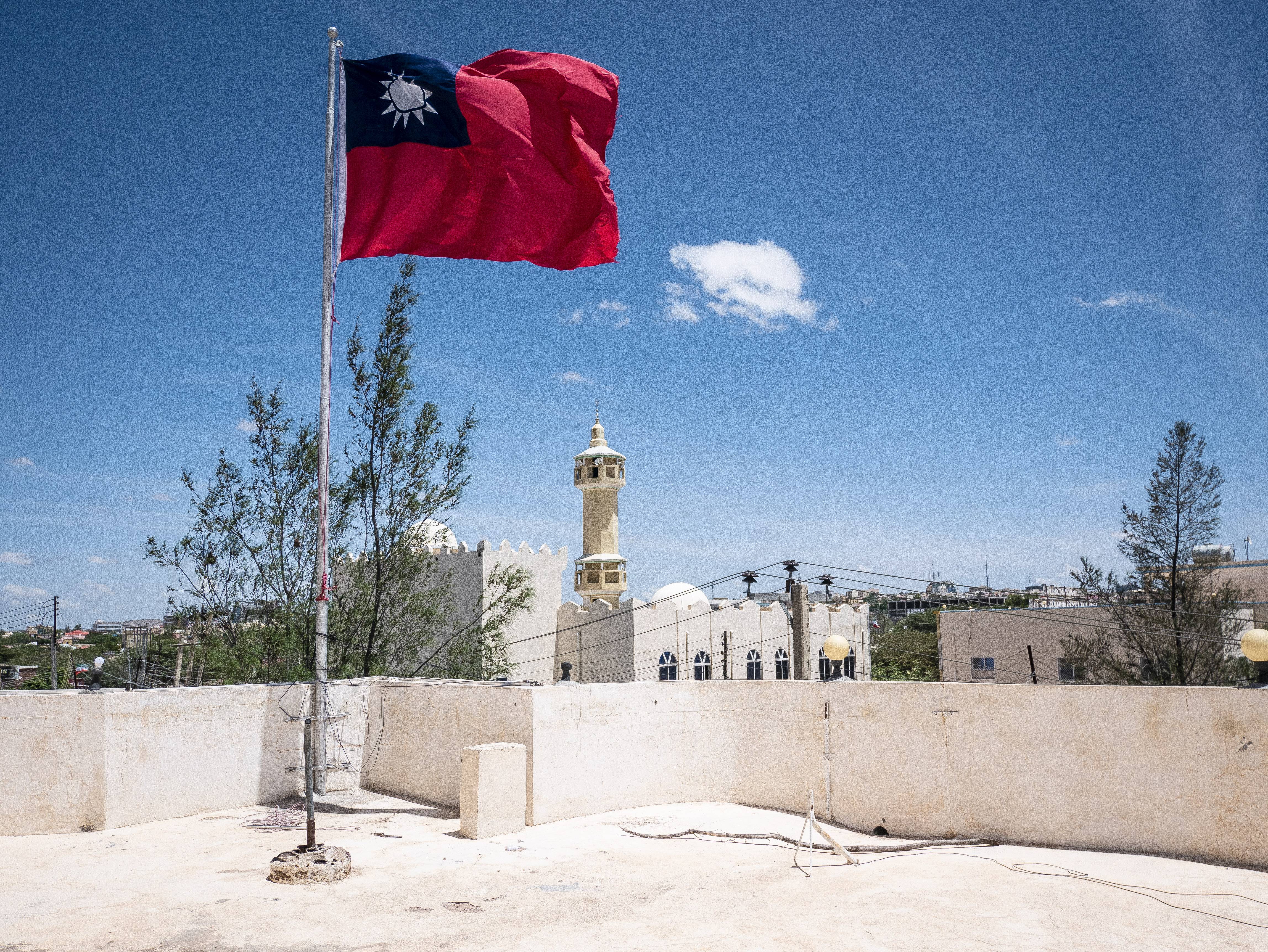 A Taiwanese flag flying in Somaliland. There is white mosque behind and the sky is blue