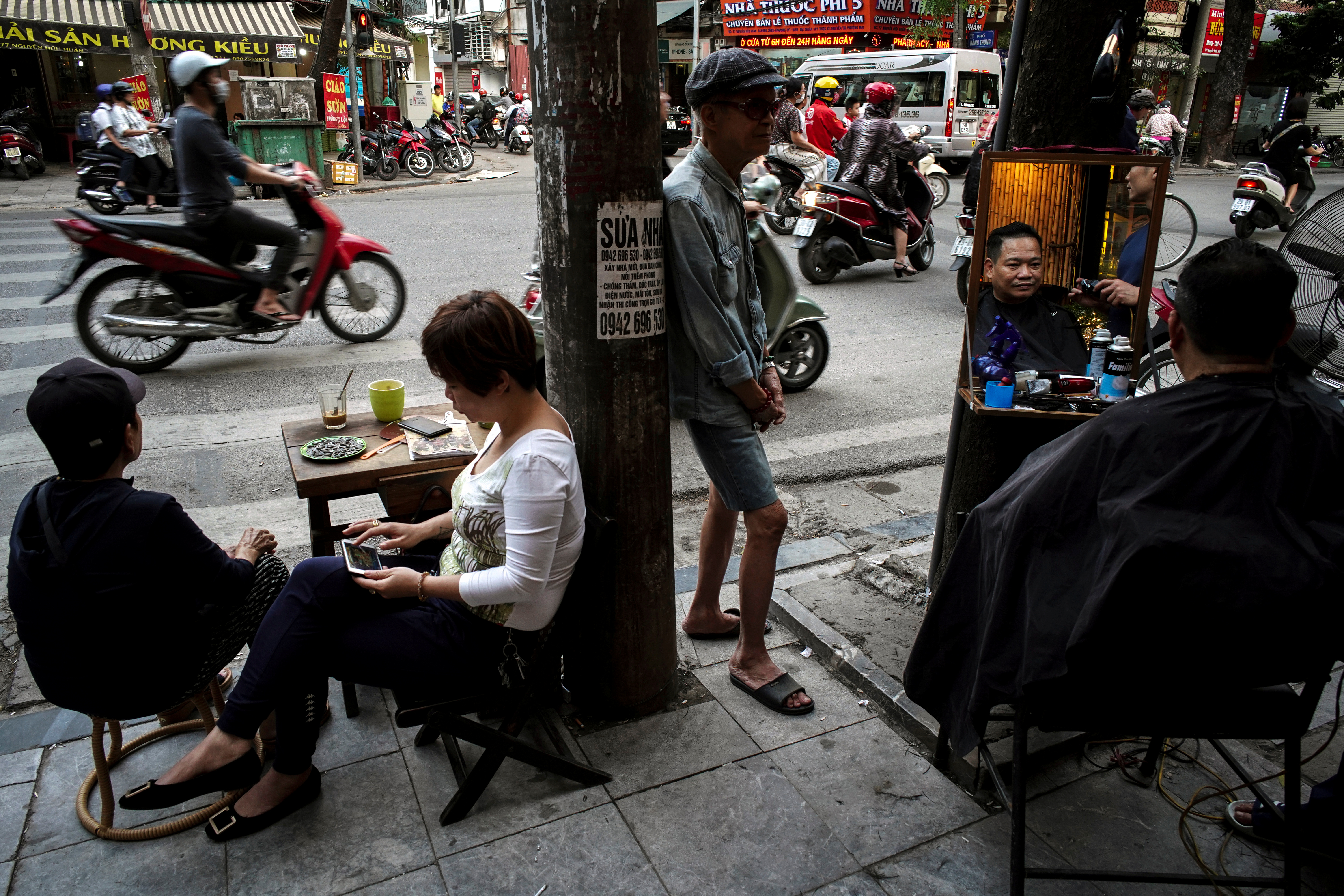 A barber gives a customer a haircut on a street in Hanoi, Vietnam, October 30, 2019. REUTERS/Atht Perawongmetha