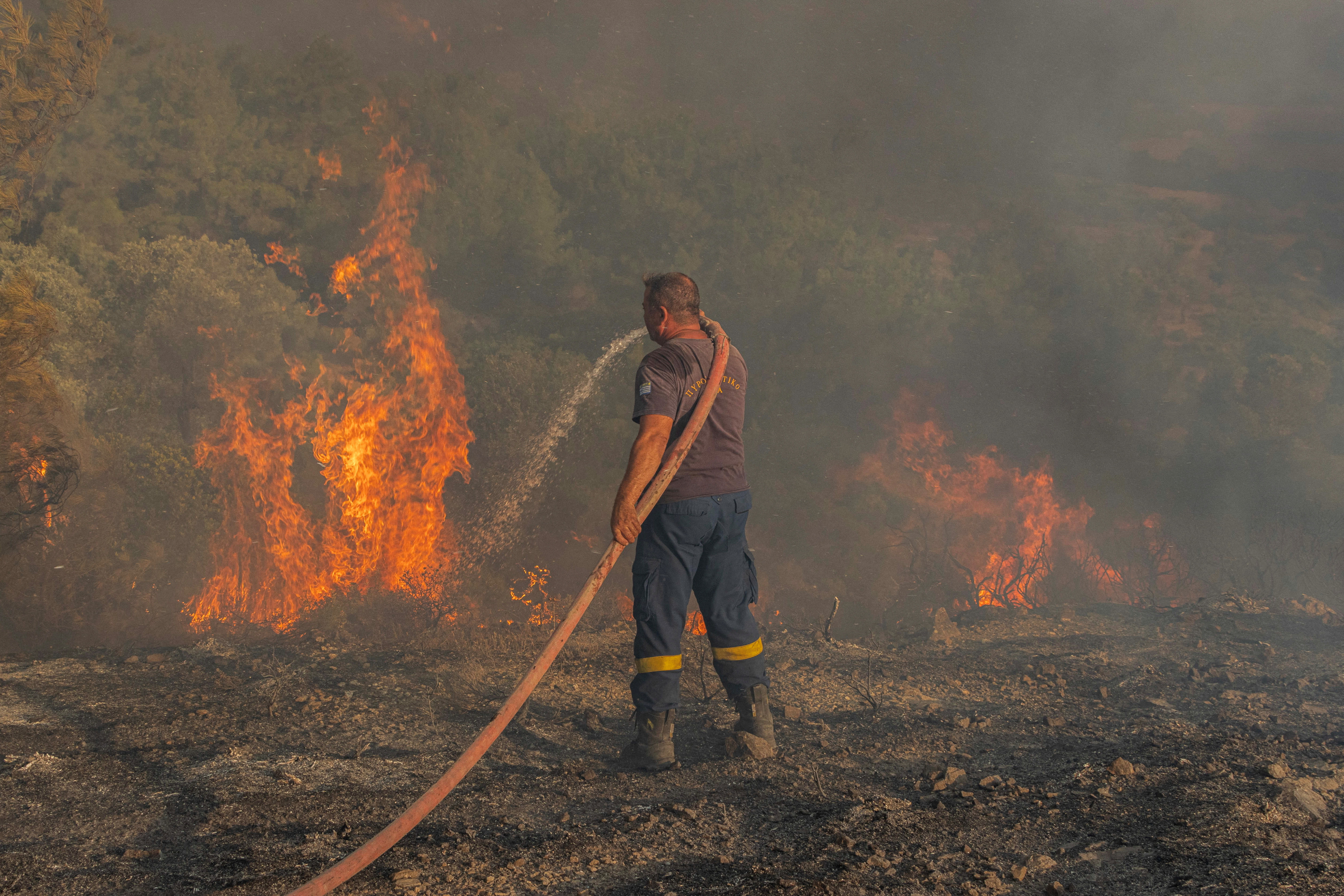 Firefighter Nektarios Kefalas tries to extinguish a wildfire burning near the village of Asklipieio, on the island of Rhodes,