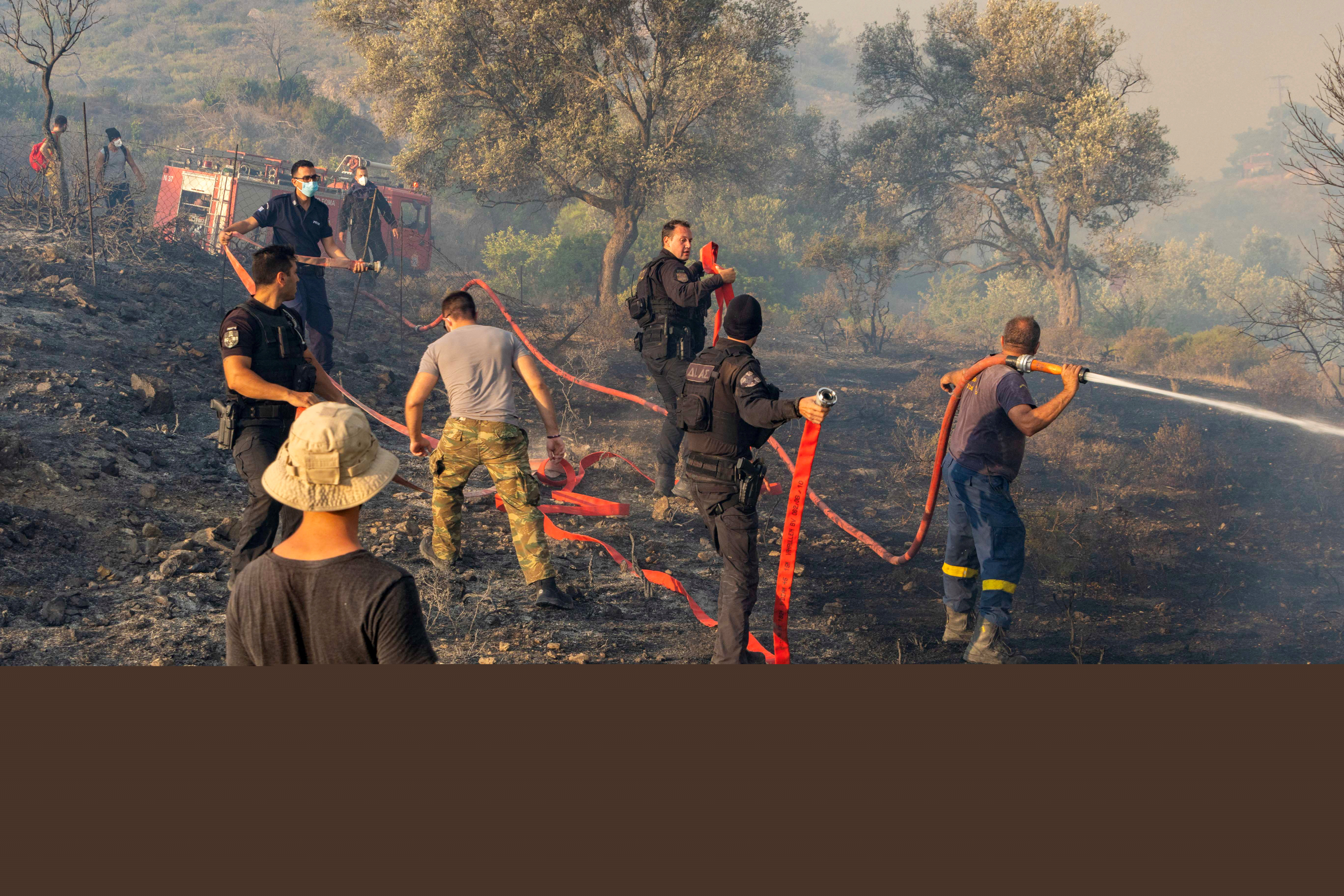 Firefighters, volunteers and police officers operate as a wildfire burns near the village of Asklipieio,
