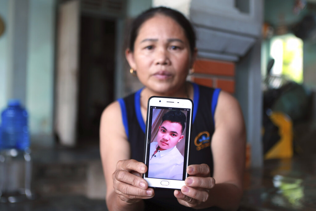 Hoang Thi Ai holds up her phone showing a photo of her son Hoang Van Tiep, who she fears is one of the possible victims in the truck deaths in England, at her home in Dien Chau district, Nghe An province, Vietnam on Monday, Oct. 28, 2019. Families in central Vietnam continue to cling on hope for the fates of their loved ones, who might be among the dead in a truck in southern England. (AP Photo/Hau Dinh)