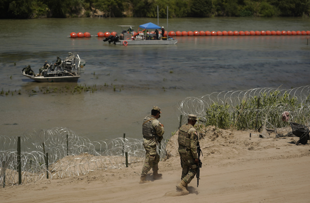 Armed guards patrol a river on the US-Mexico border