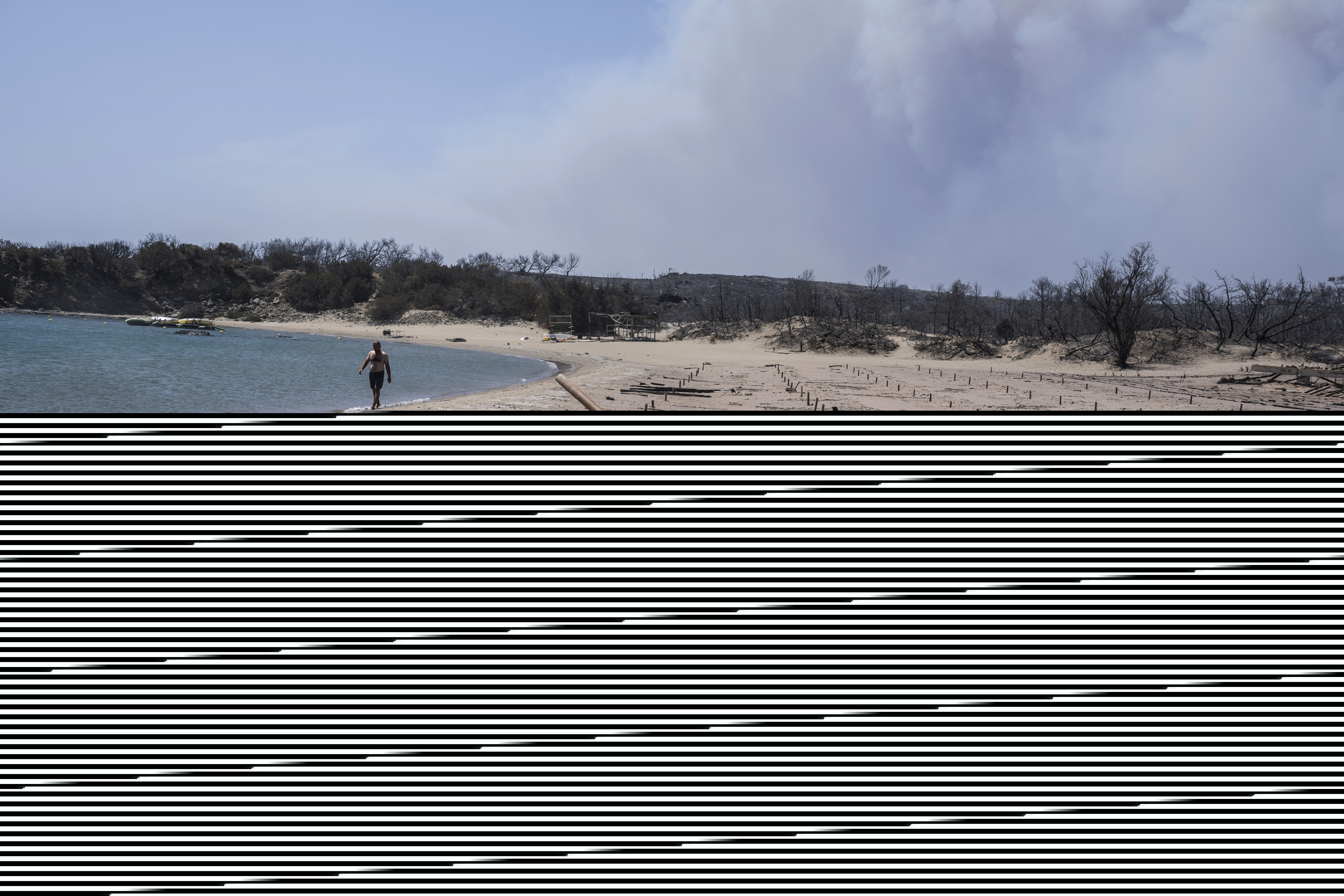 A man walks next to the burnt sunbeds and umbrellas at a beach on the Aegean Sea island of Rhodes,